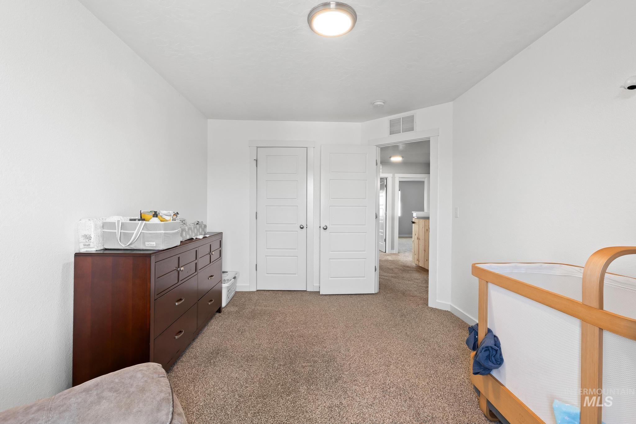 Bedroom with light colored carpet and a closet