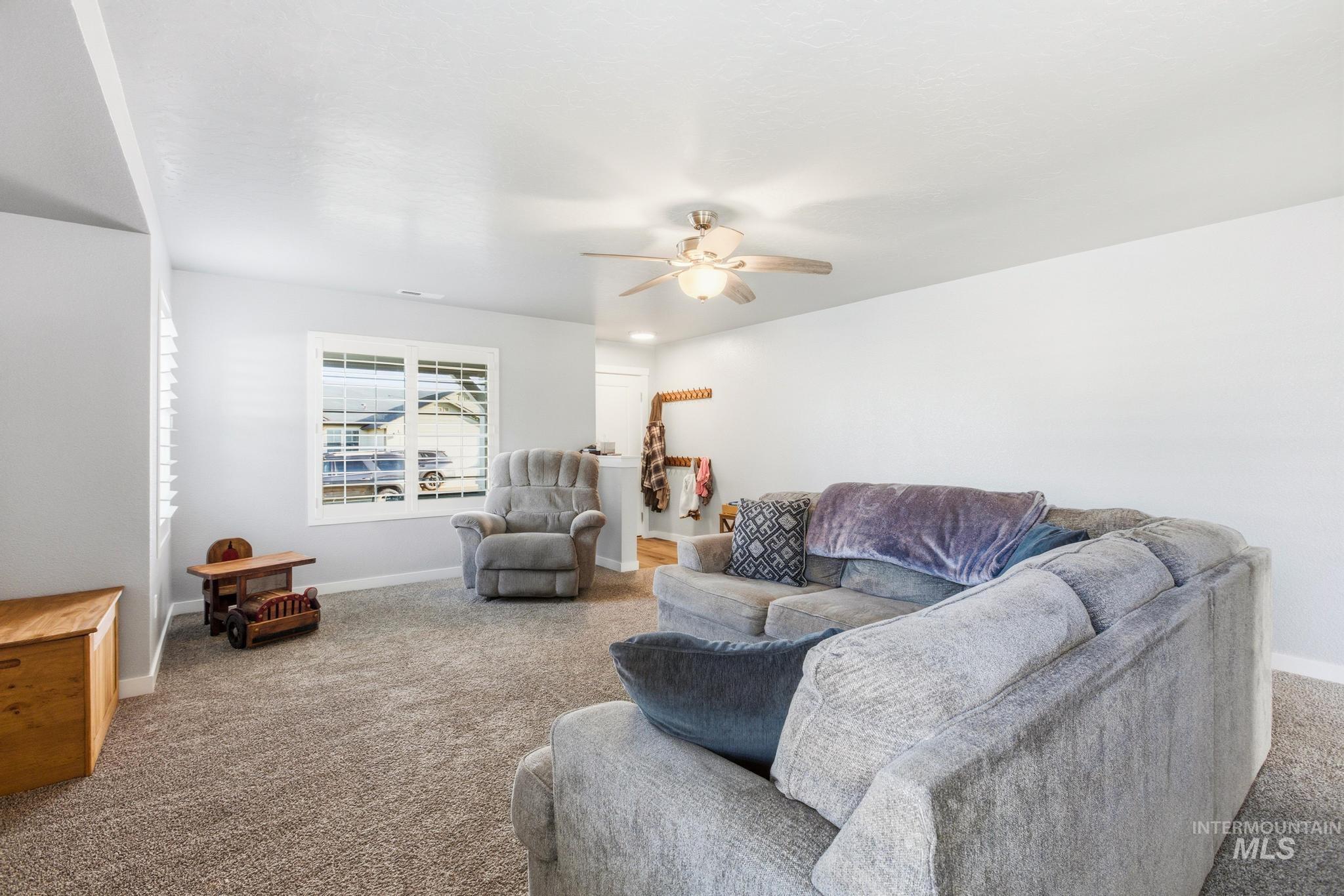 Carpeted living room featuring baseboards and a ceiling fan