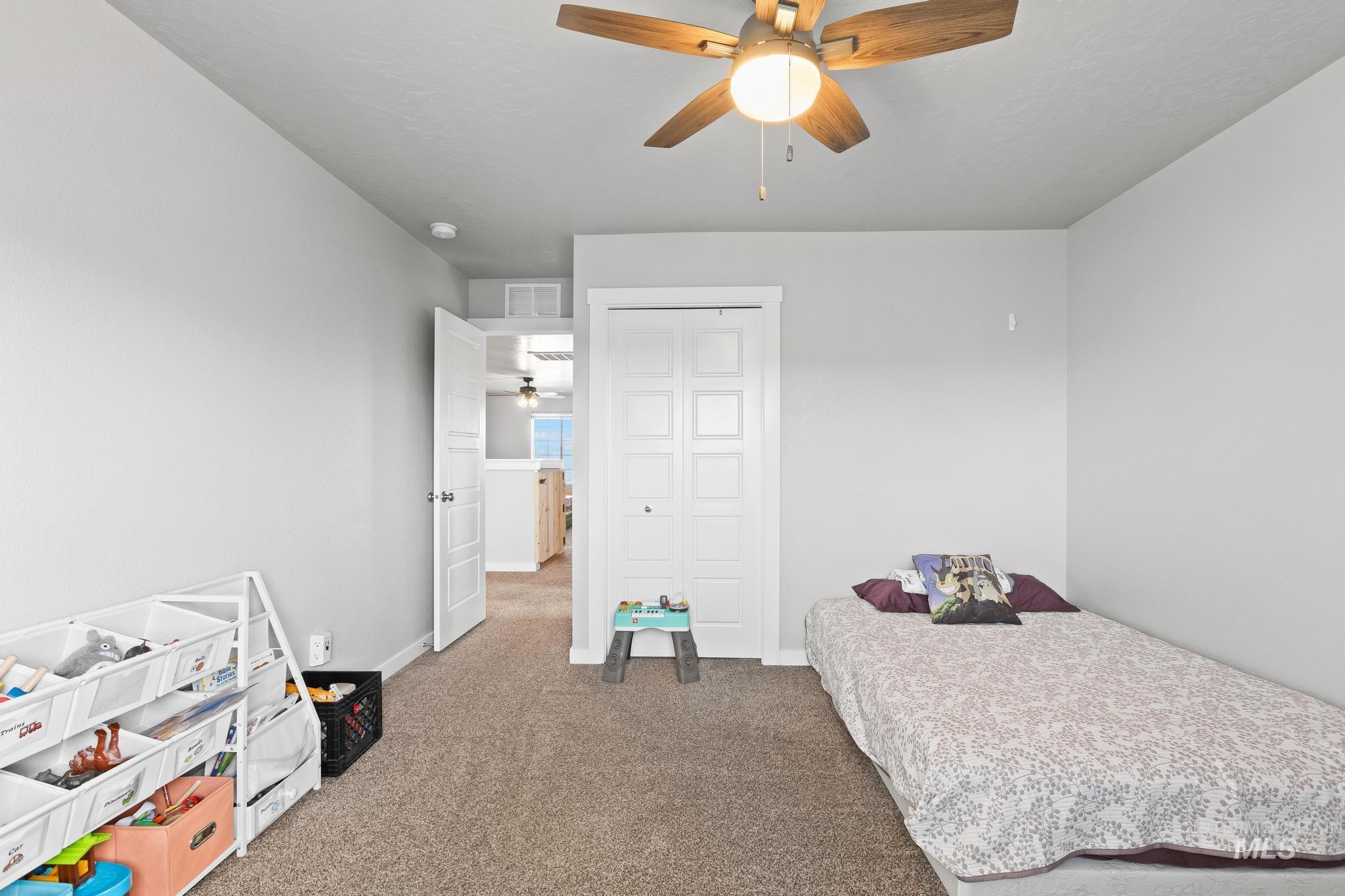 Carpeted bedroom featuring ceiling fan and a closet