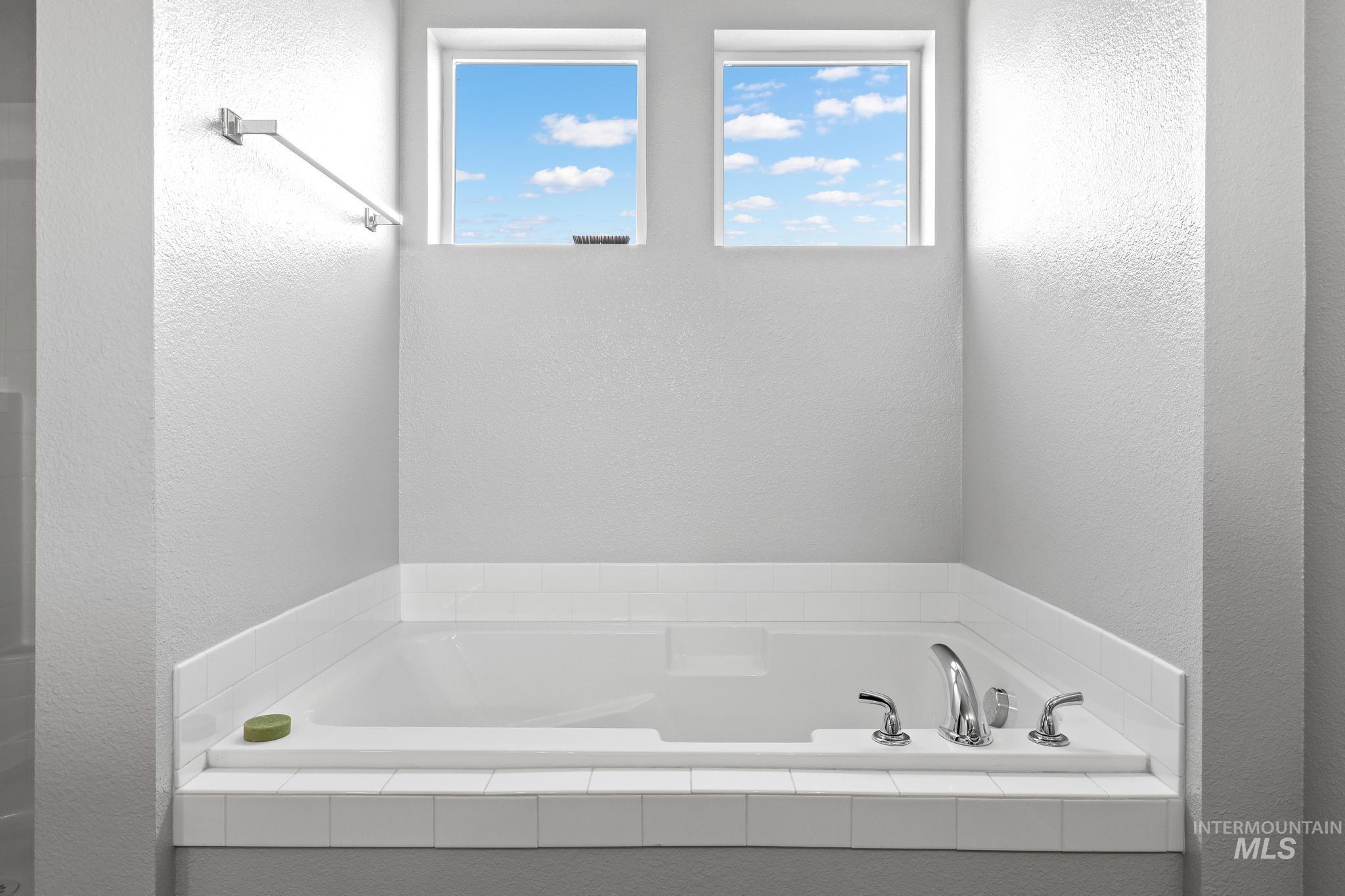 Full bathroom featuring a textured wall and a bath