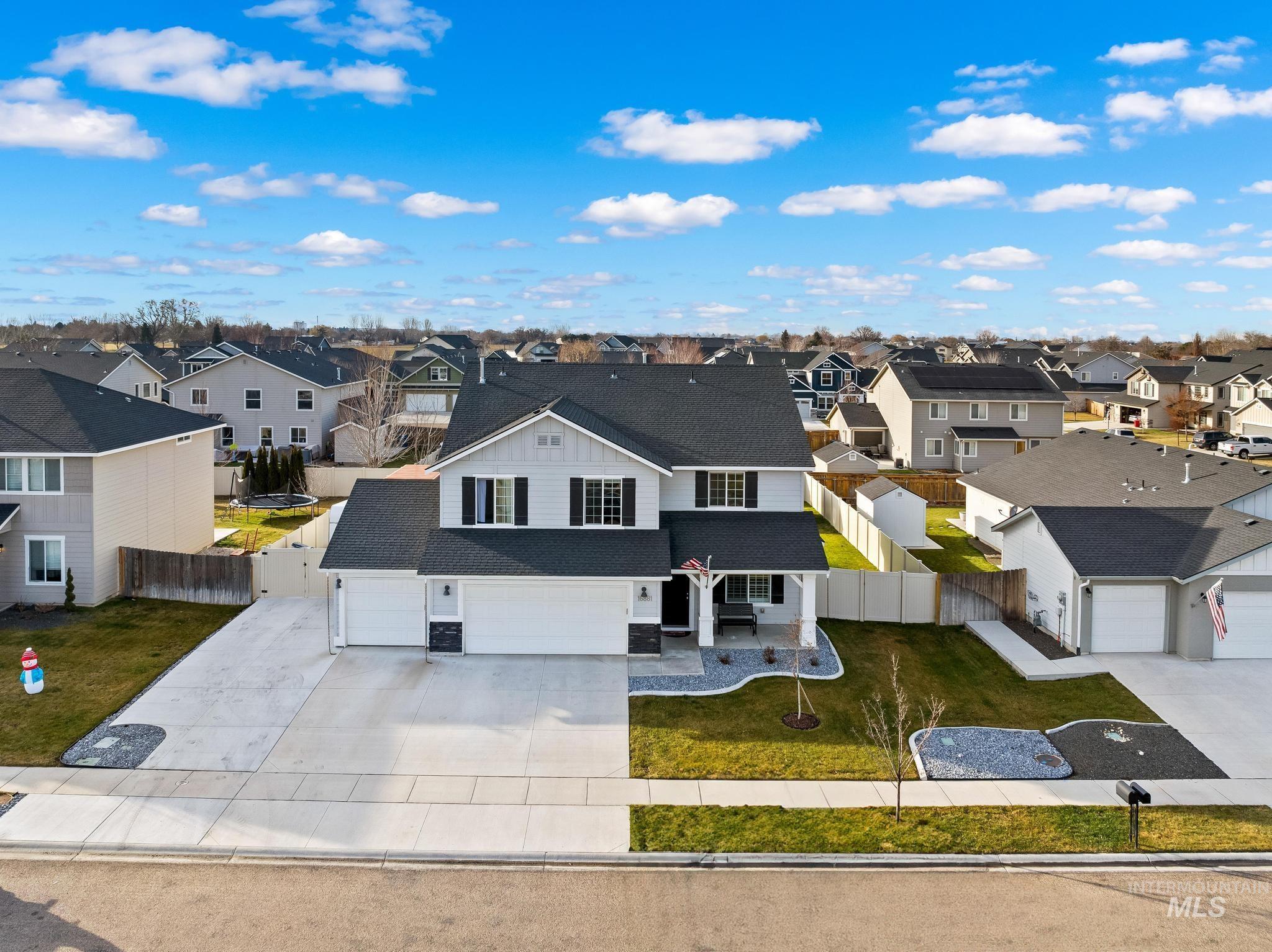 View of front of home featuring a residential view, a shingled roof, concrete driveway, a garage, and a patio