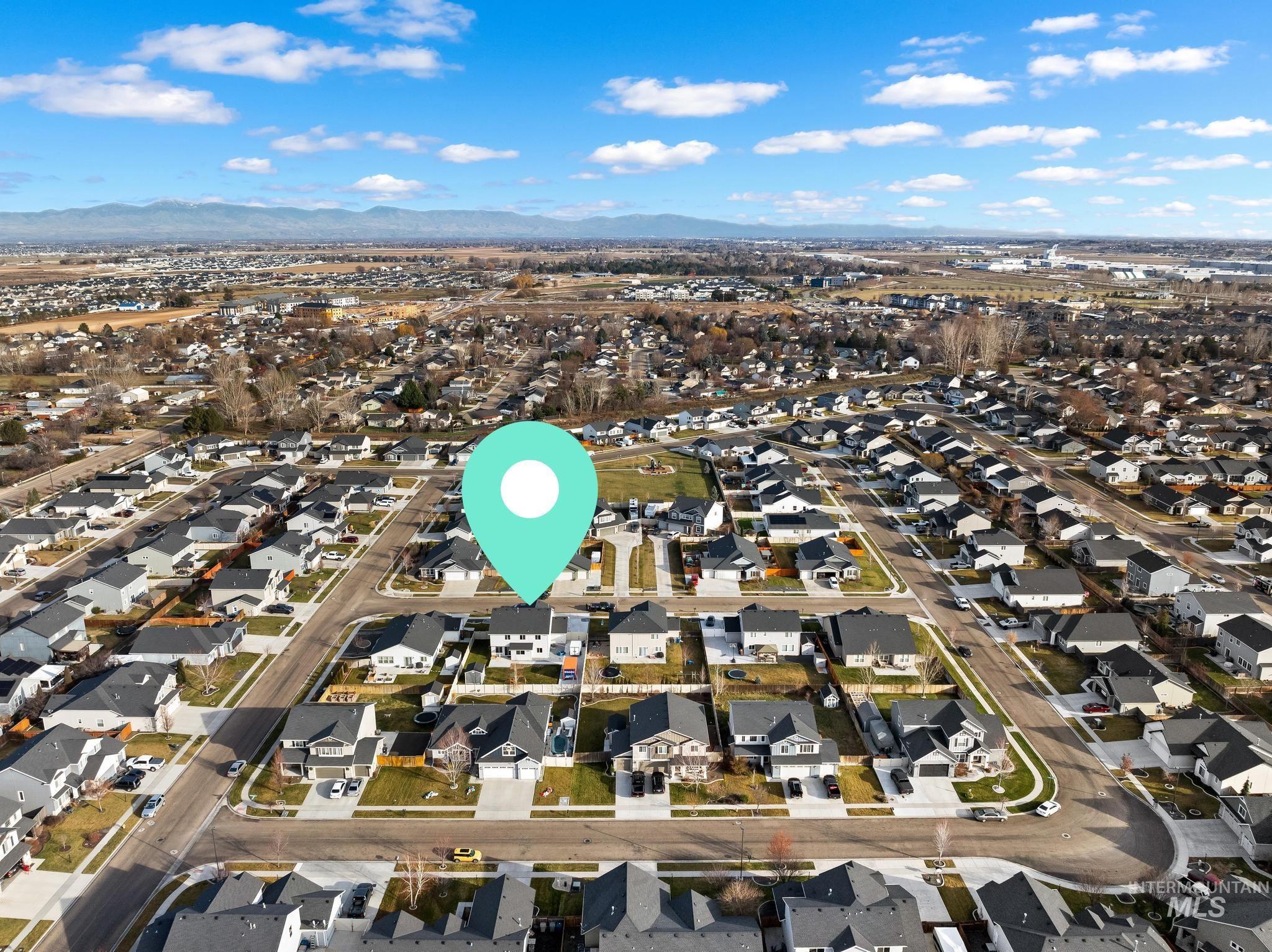 Aerial view of property and surrounding area with nearby suburban area and a mountain backdrop
