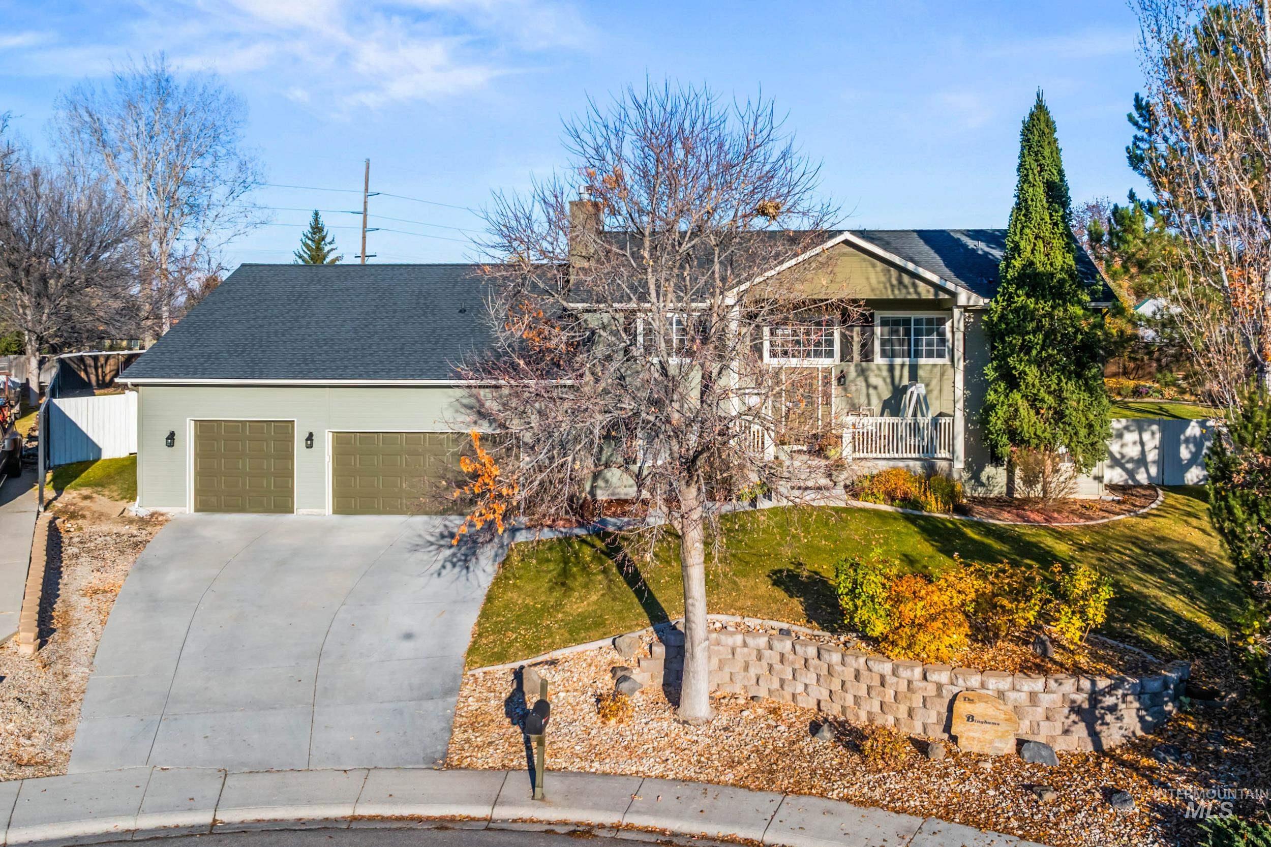 View of front of property featuring driveway, roof with shingles, an attached garage, a balcony, and a chimney
