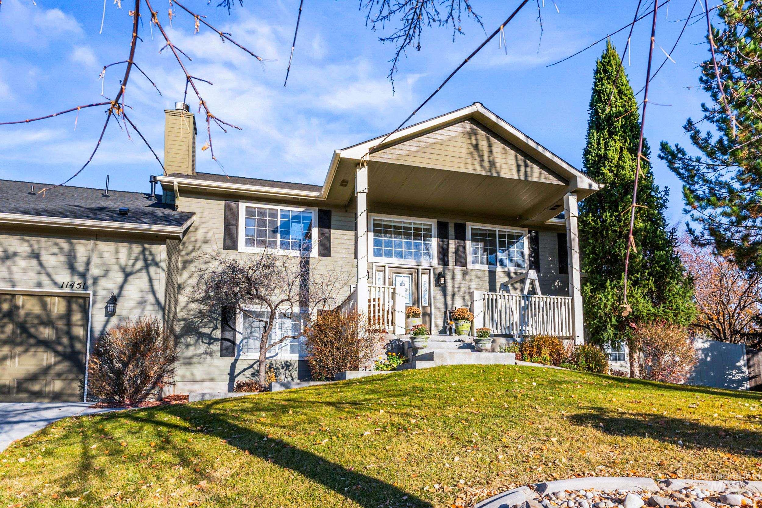 View of front of property featuring a front lawn, a chimney, covered porch, brick siding, and a shingled roof