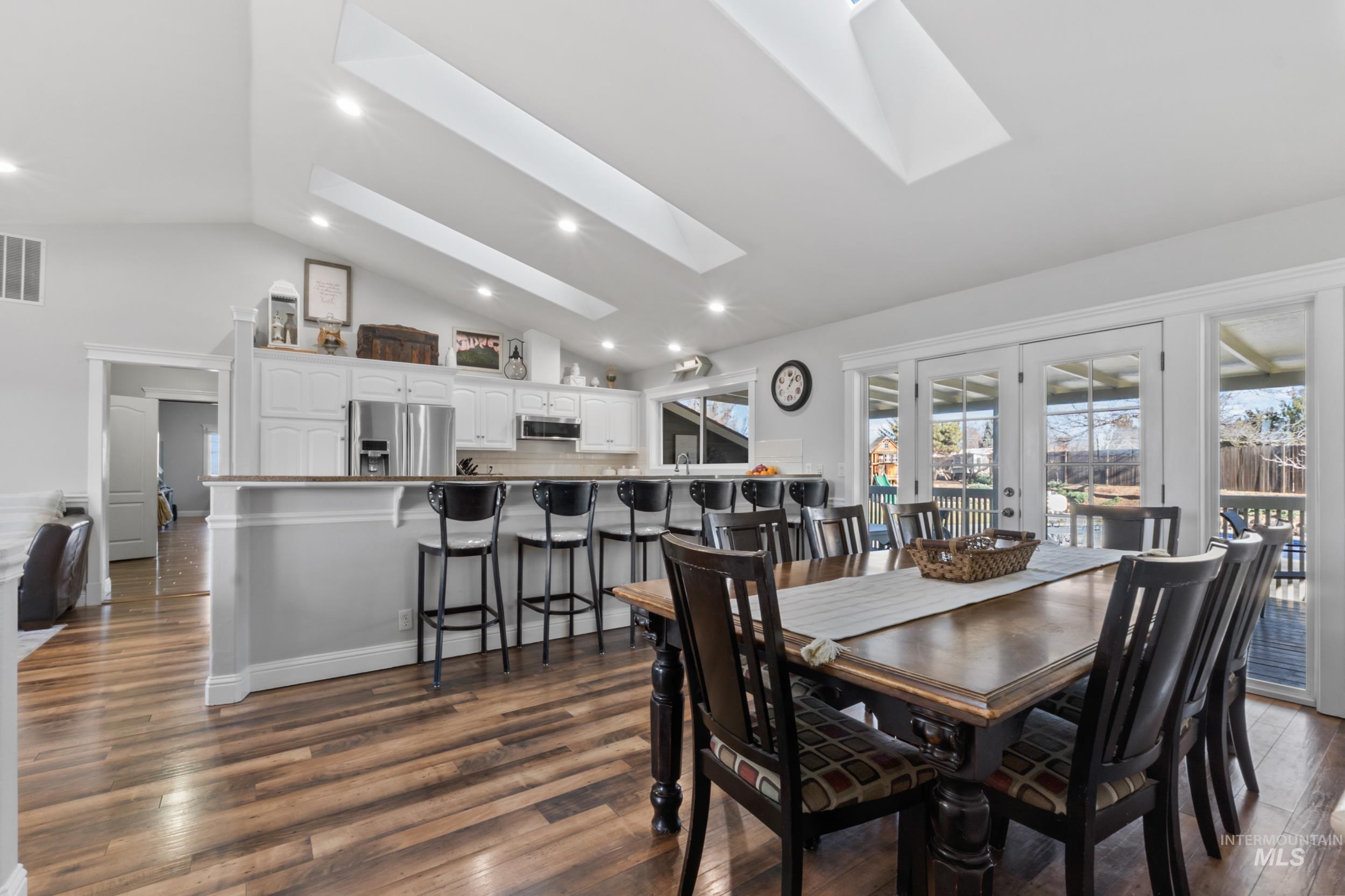 Dining room featuring recessed lighting, french doors, dark wood finished floors, a skylight, and high vaulted ceiling