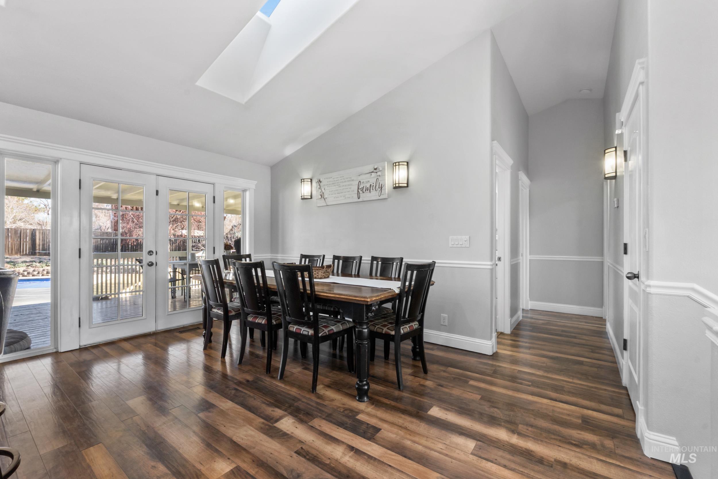 Dining room featuring french doors, vaulted ceiling, a skylight, and dark wood-style floors