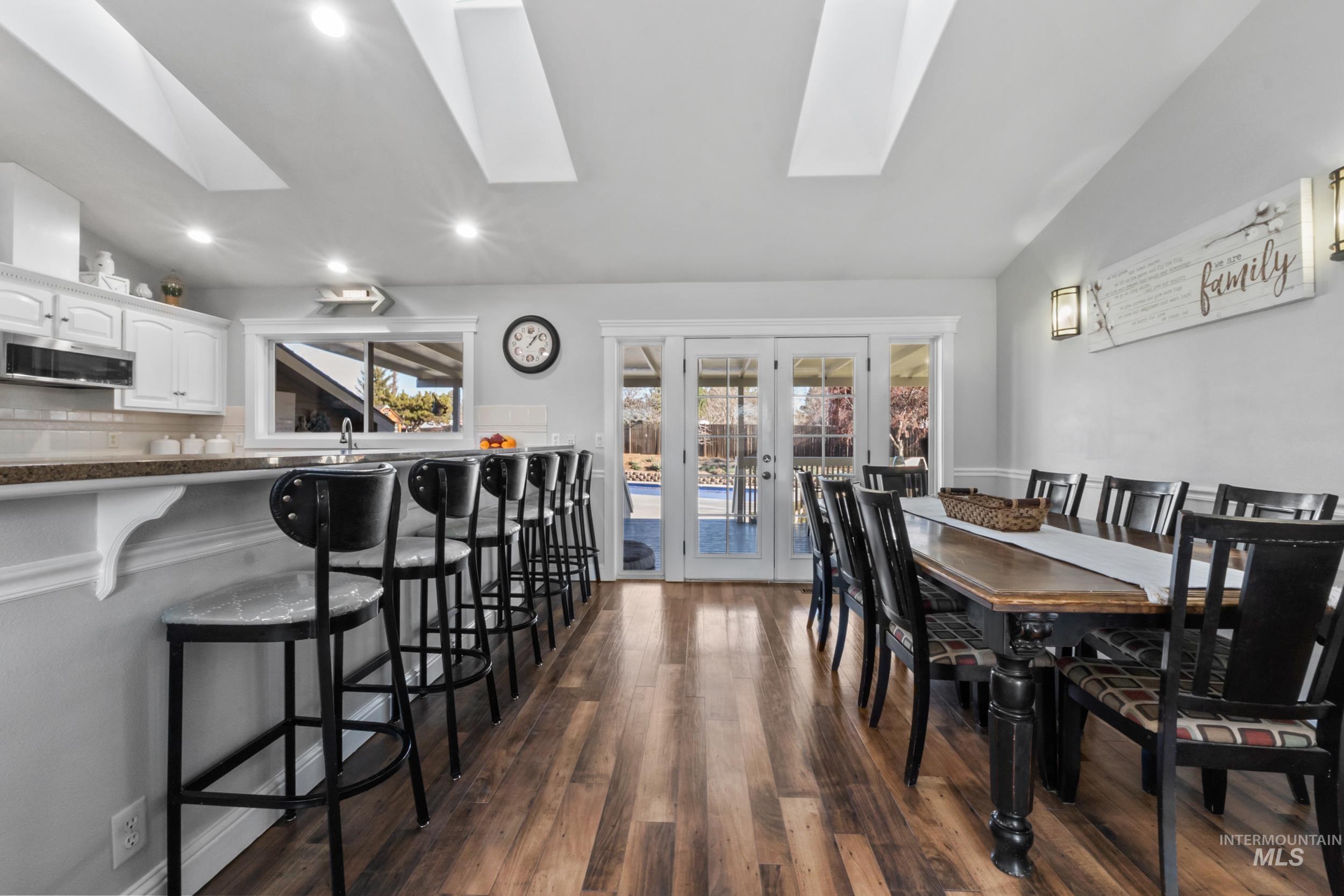 Dining space with vaulted ceiling, french doors, dark wood-style floors, and recessed lighting