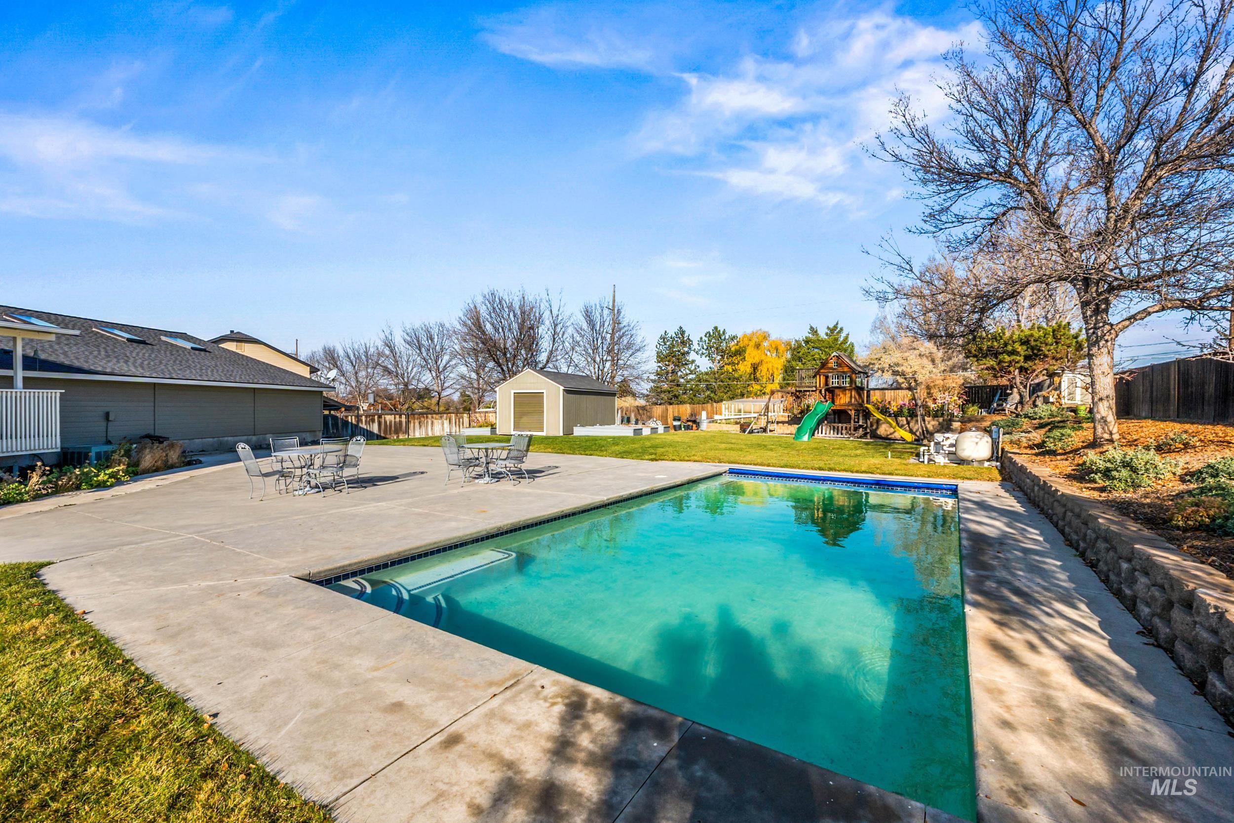 View of pool featuring a fenced backyard, a patio area, a playground, outdoor dining space, and a shed