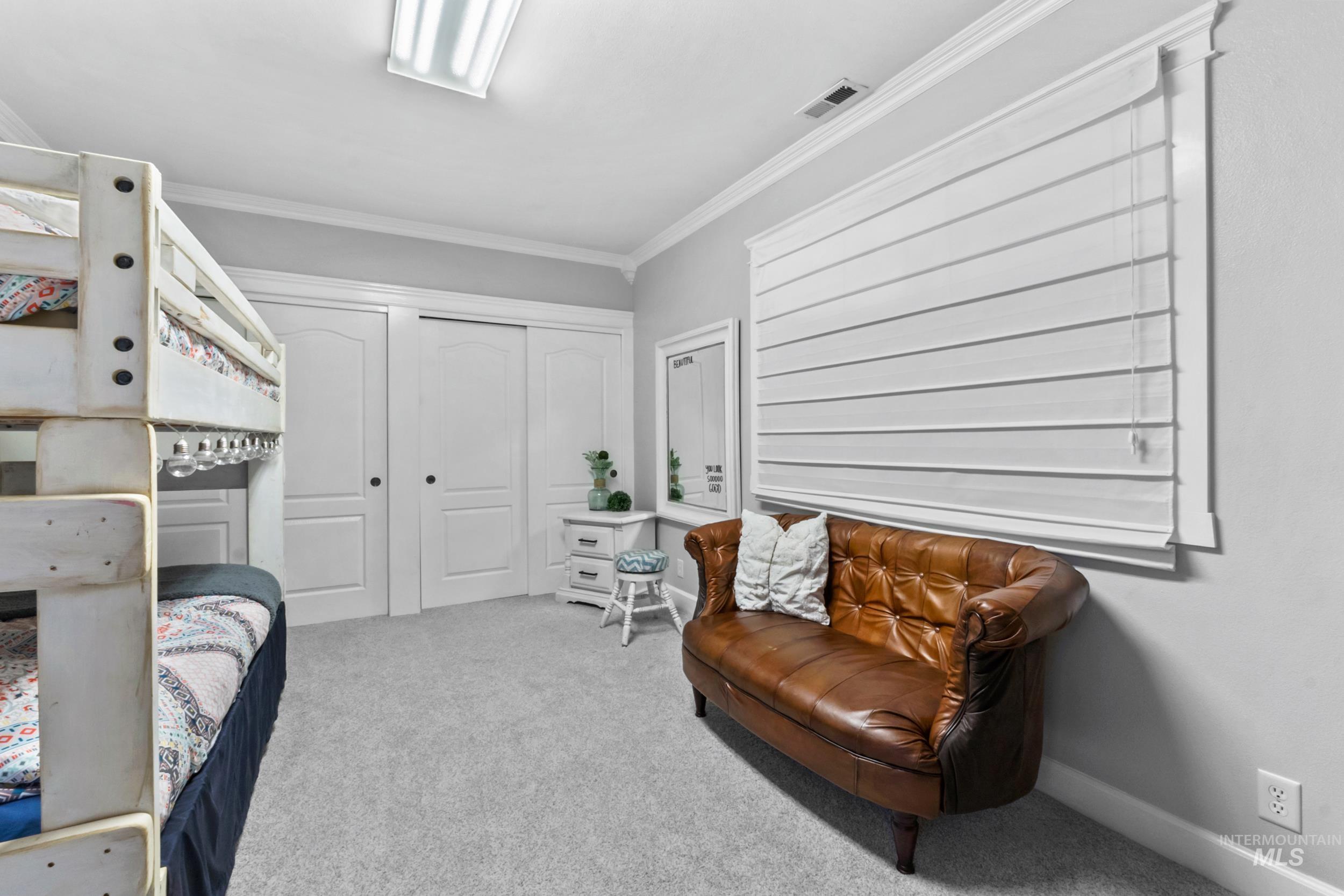 Bedroom featuring light colored carpet, ornamental molding, and a closet