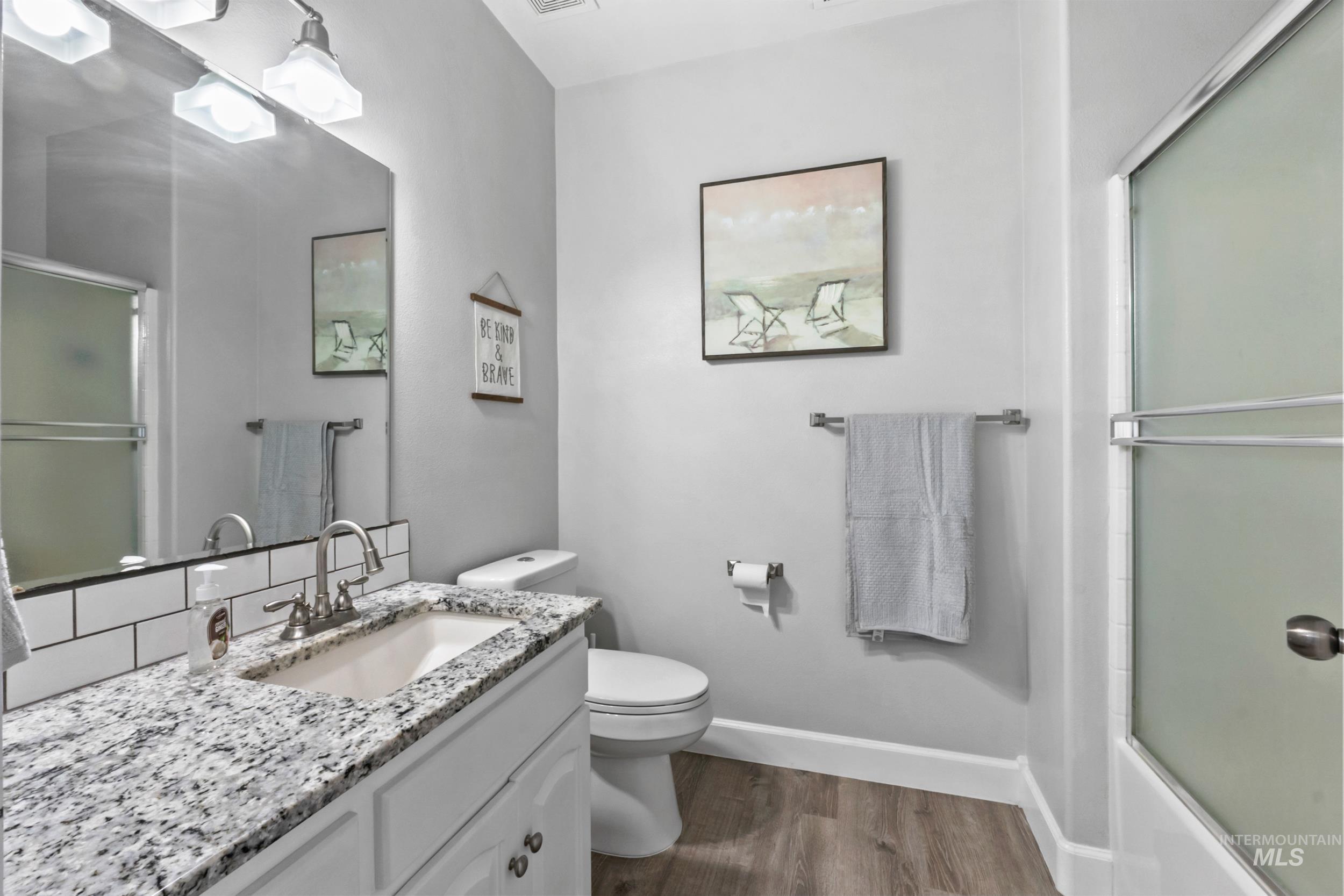 Full bath featuring vanity, dark wood-style floors, and shower / bath combination with glass door