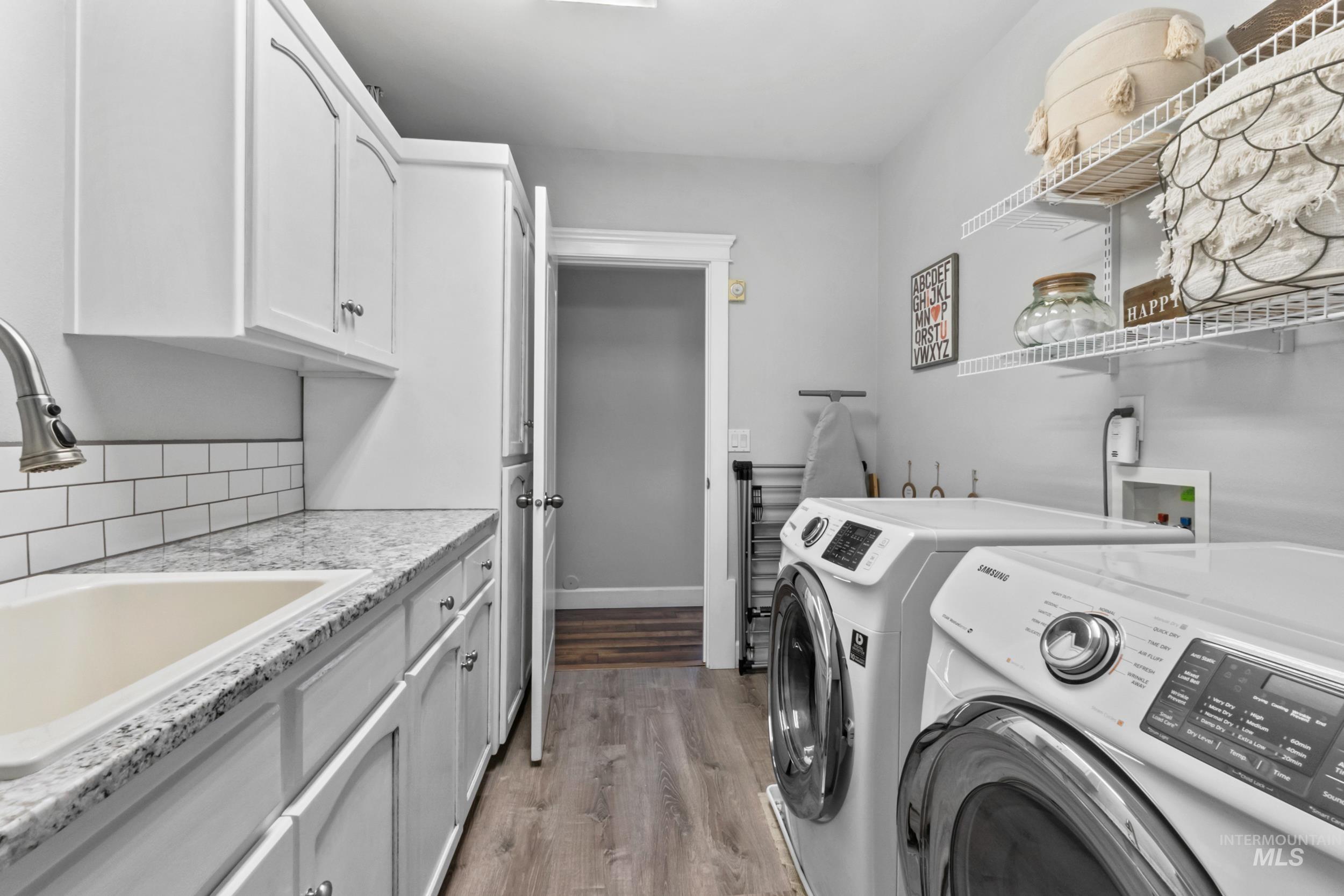 Laundry room with light wood-style floors, washer and dryer, and cabinet space