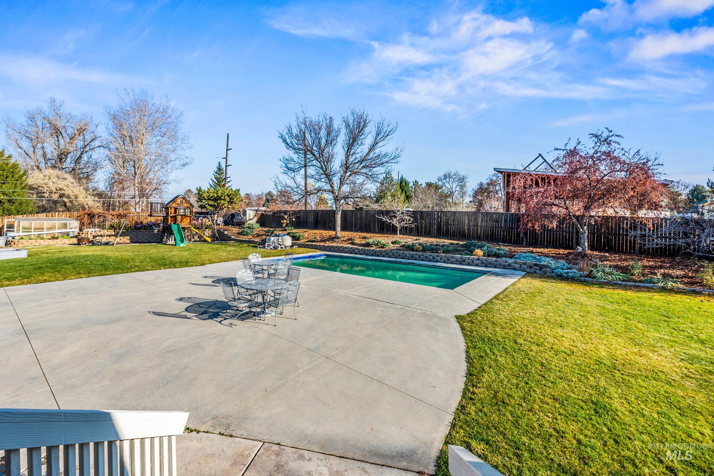 View of swimming pool with a patio area, a playground, and a fenced backyard