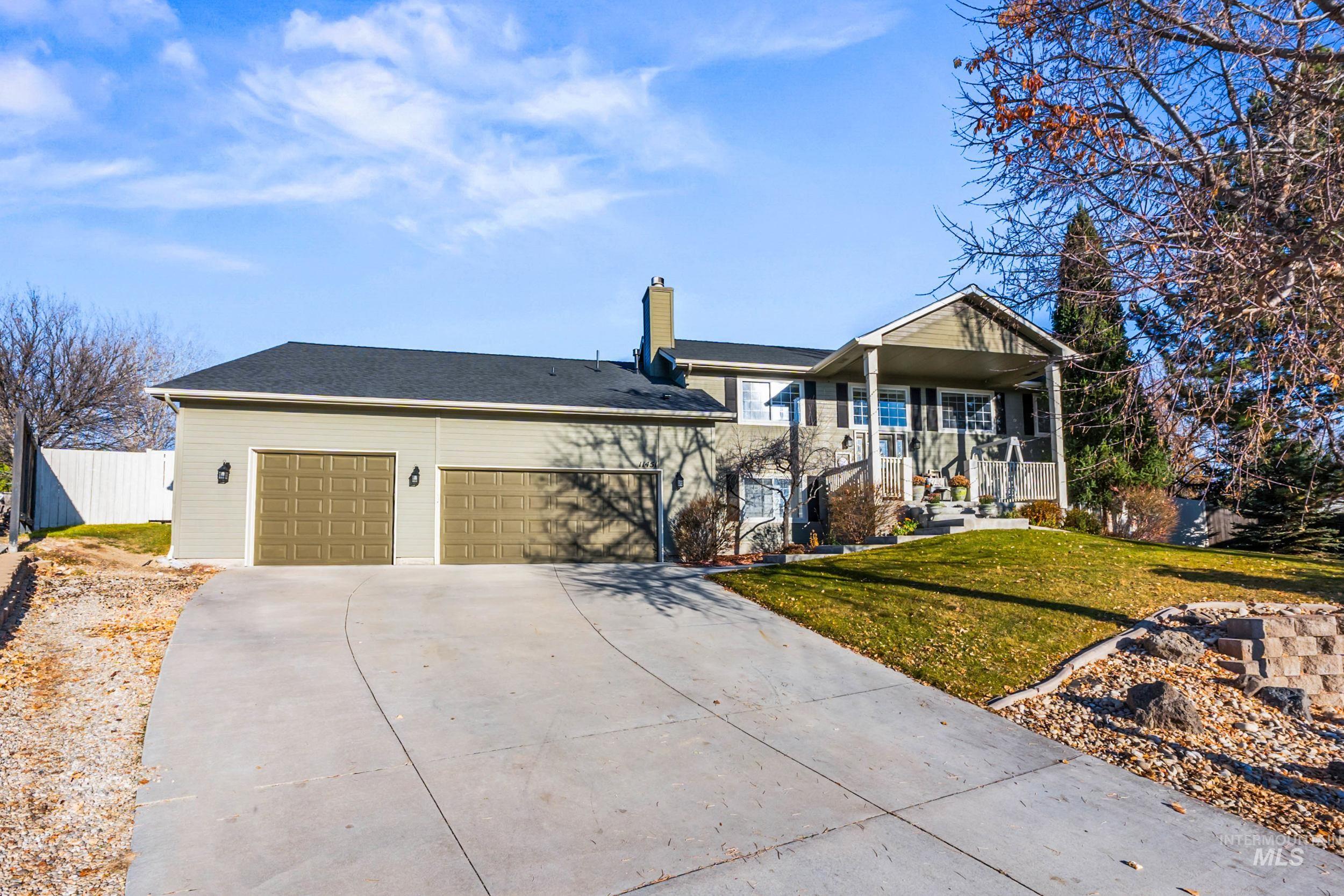 View of front of house with driveway, a chimney, an attached garage, and covered porch
