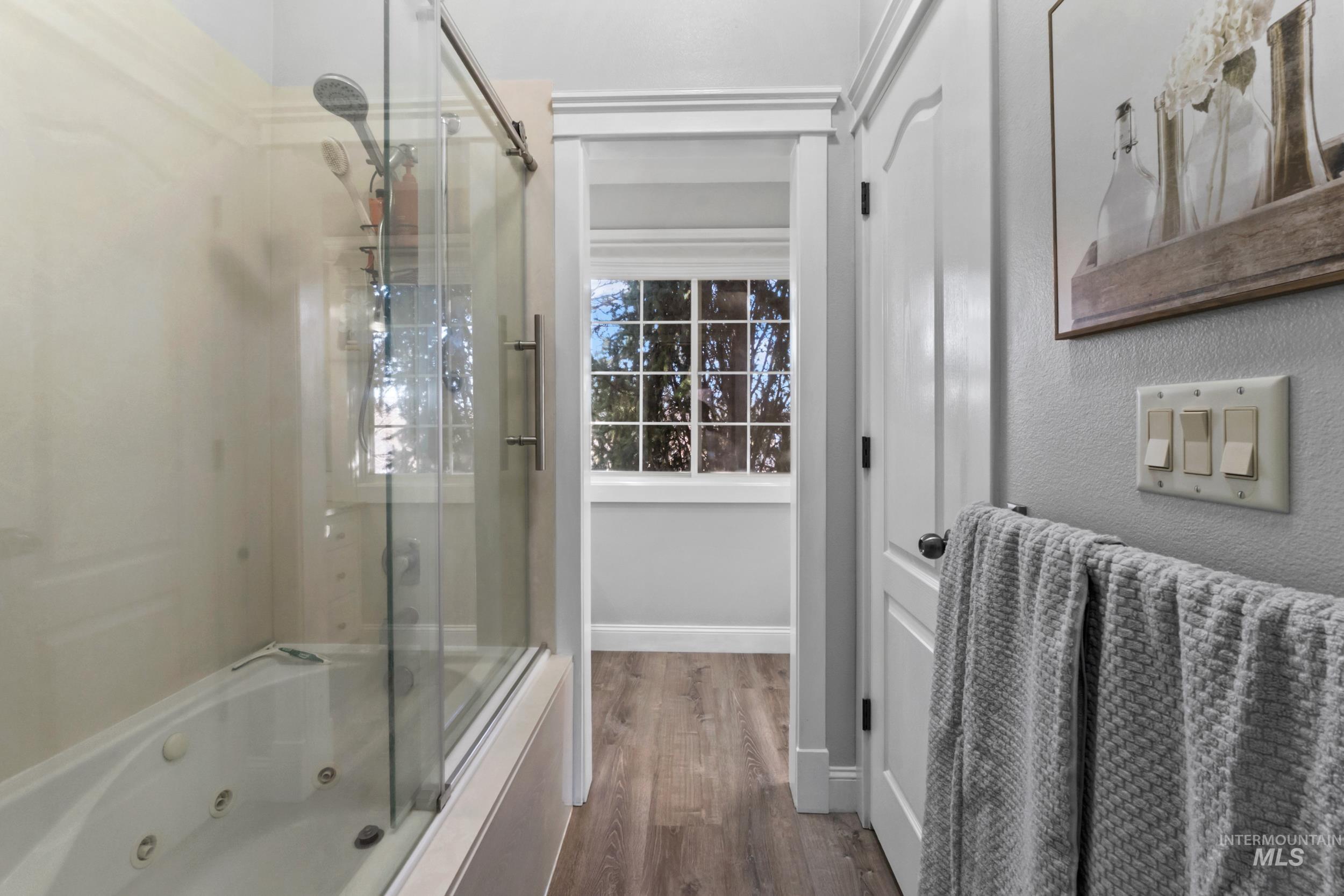 Bathroom featuring a combined bath / shower with jetted tub and wood finished floors