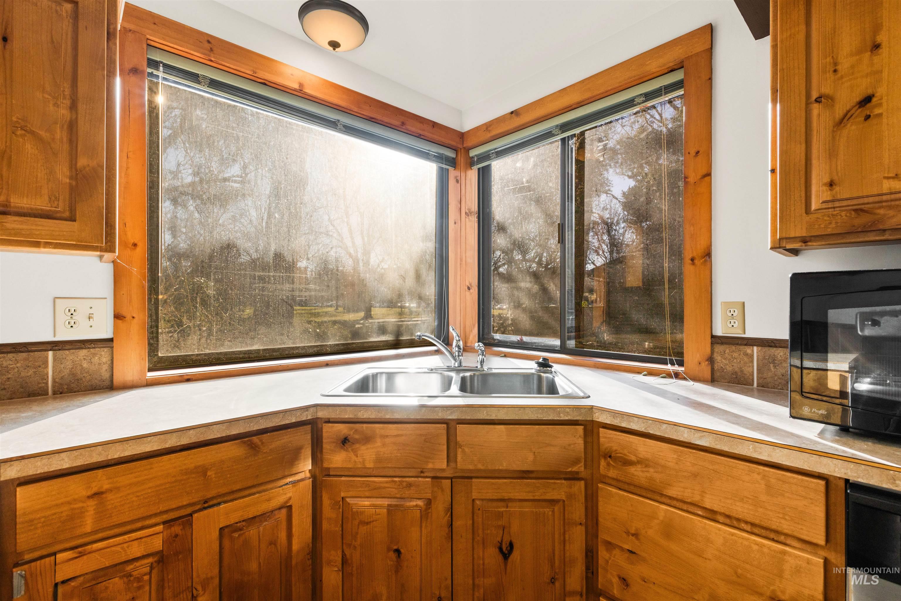 Kitchen featuring brown cabinets, light countertops, and black microwave
