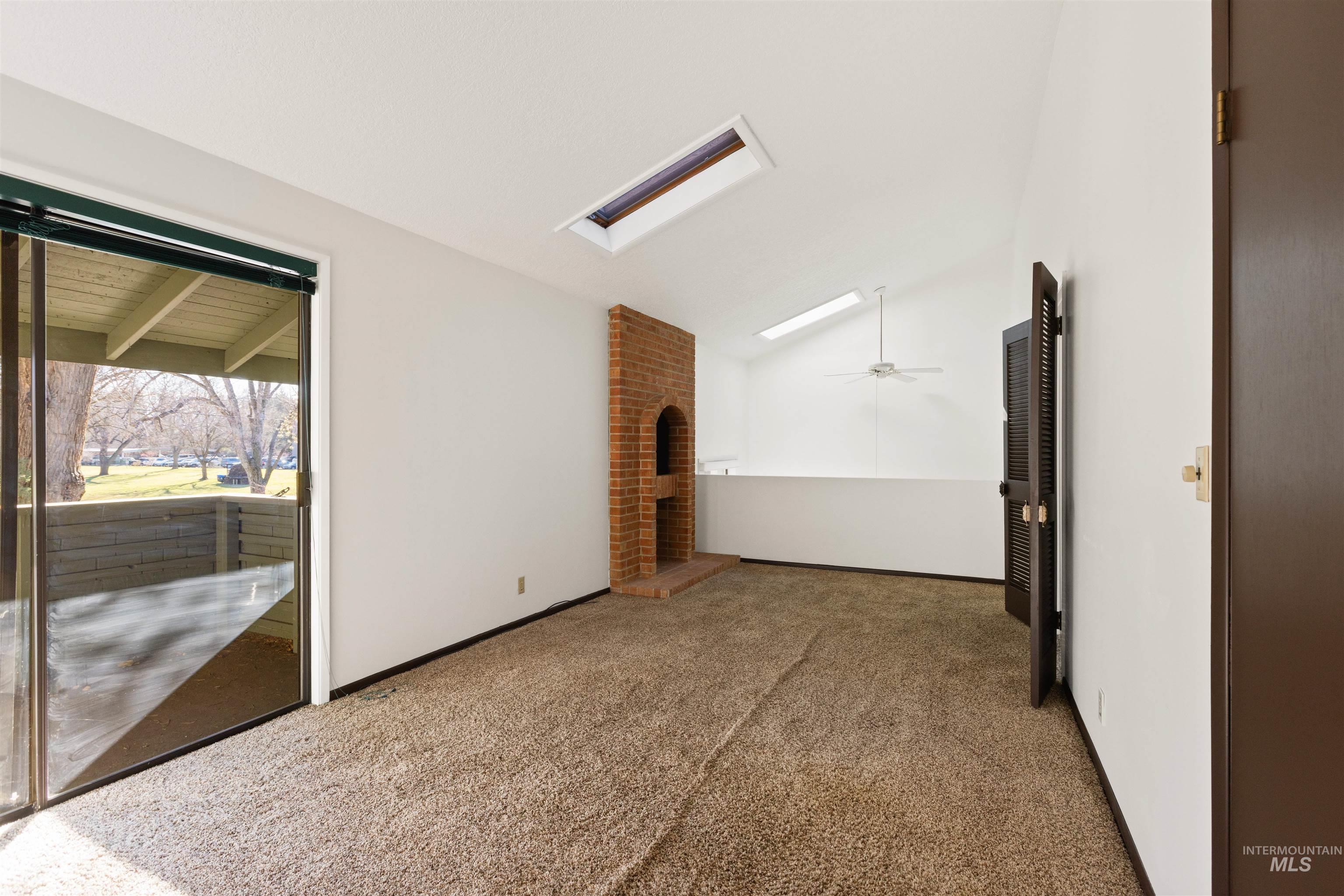 Carpeted empty room featuring lofted ceiling and a skylight