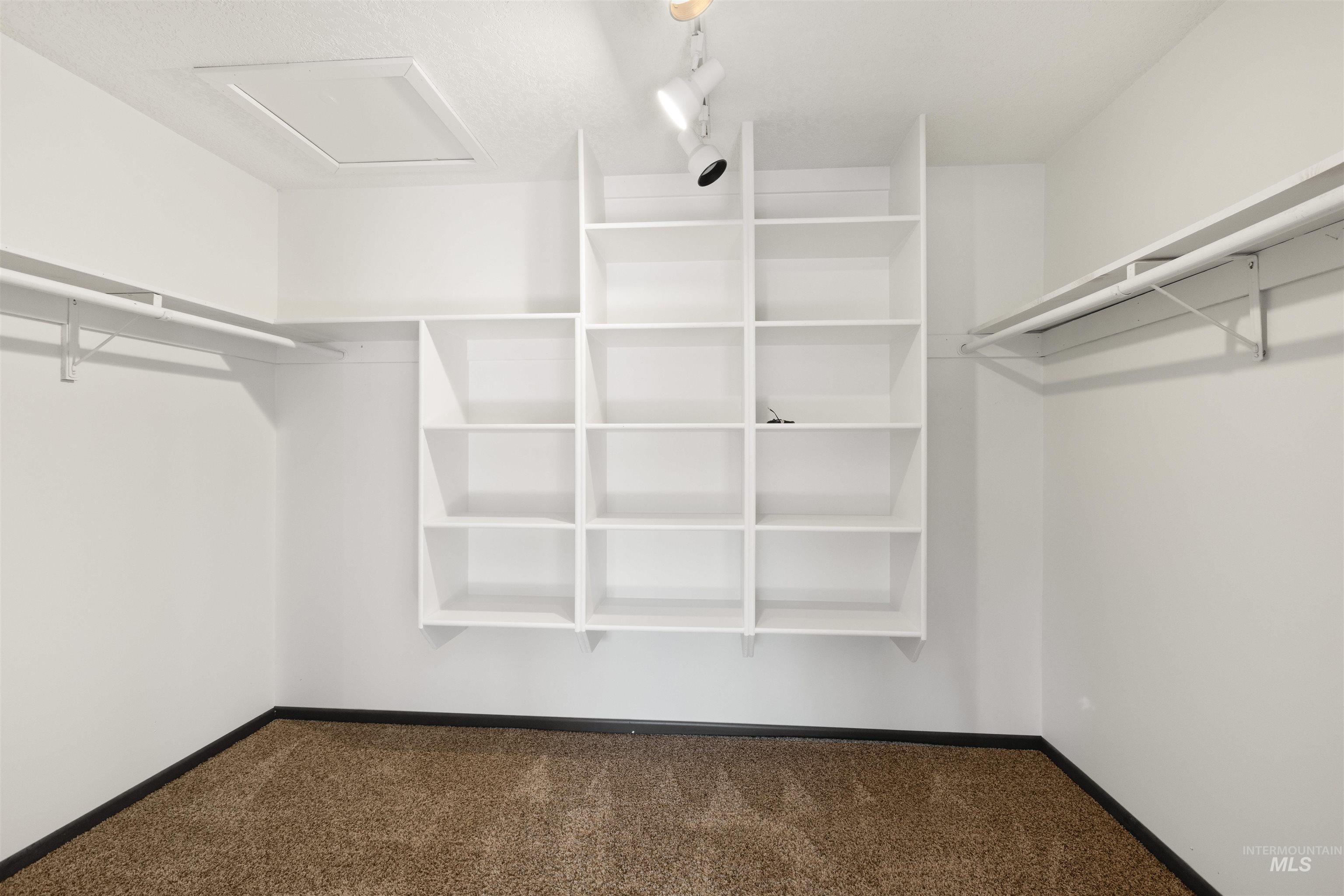 Spacious closet featuring dark colored carpet and attic access