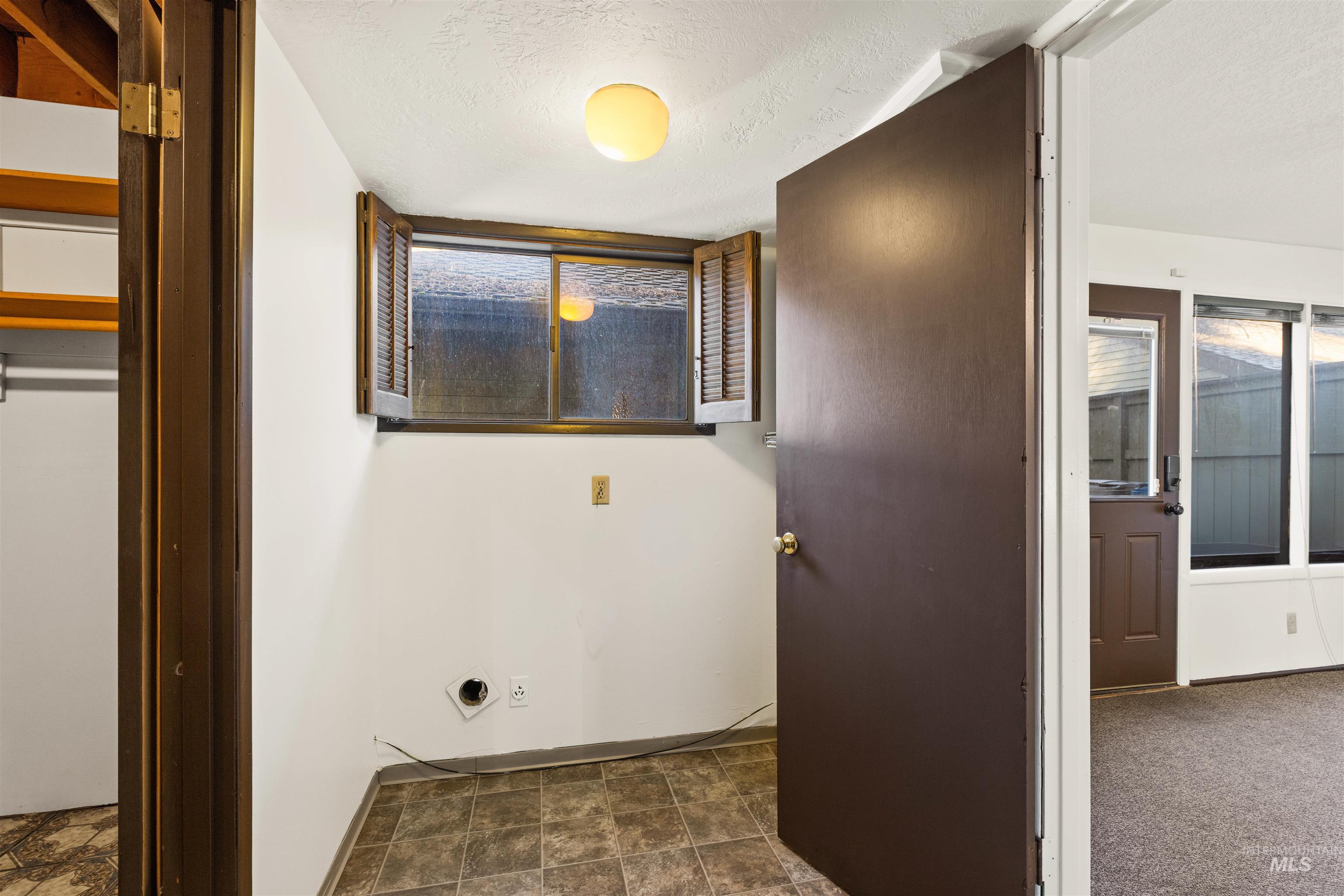 Laundry room featuring a textured ceiling and stone finish floors