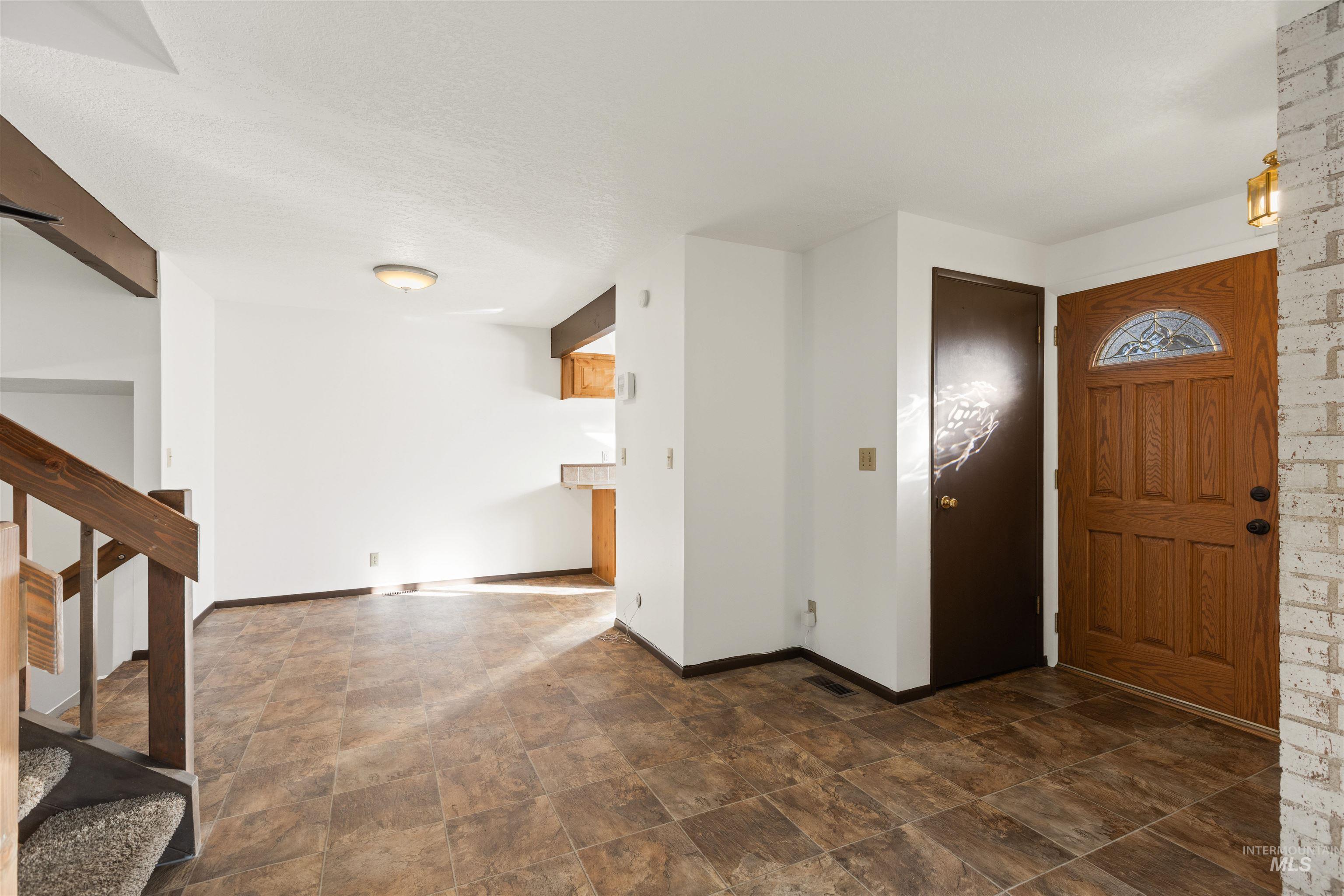 Entryway with stairs, stone finish floors, and a textured ceiling