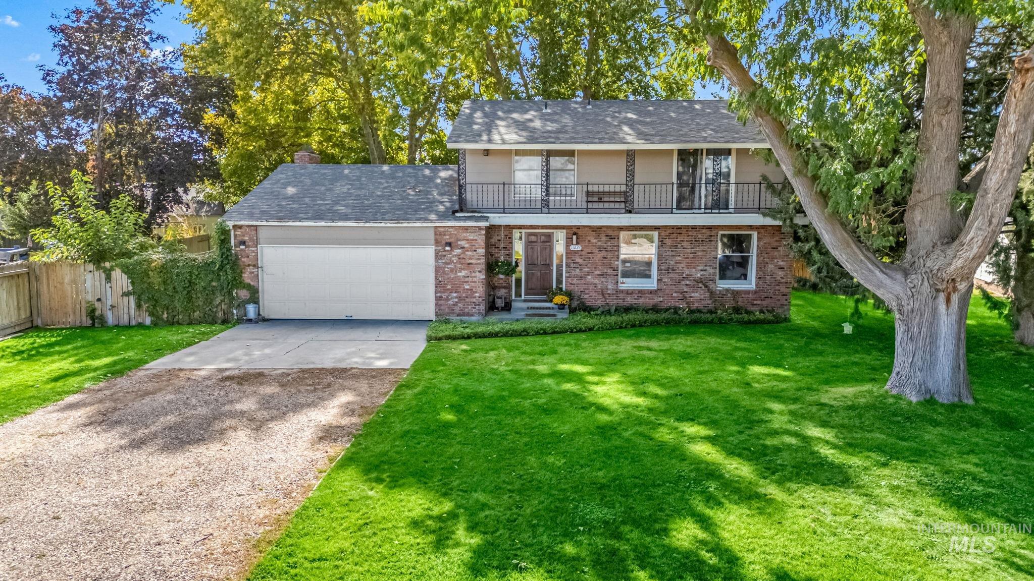 View of front of home with driveway, a balcony, an attached garage, brick siding, and a shingled roof