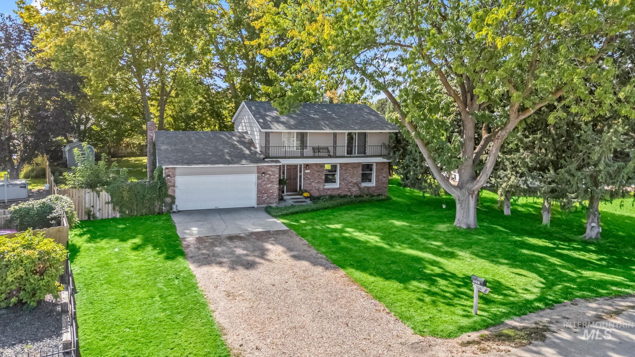 Traditional-style home with concrete driveway, brick siding, a balcony, roof with shingles, and a garage