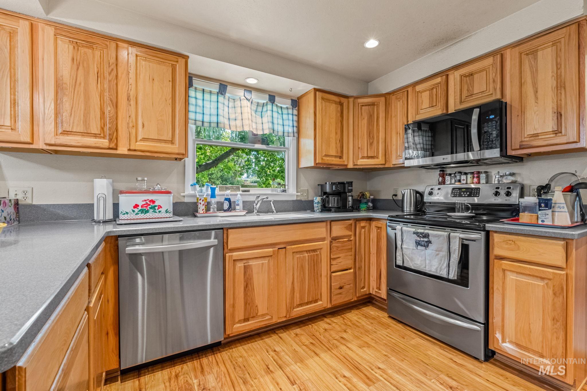 Kitchen with appliances with stainless steel finishes, light wood-style flooring, recessed lighting, and dark countertops