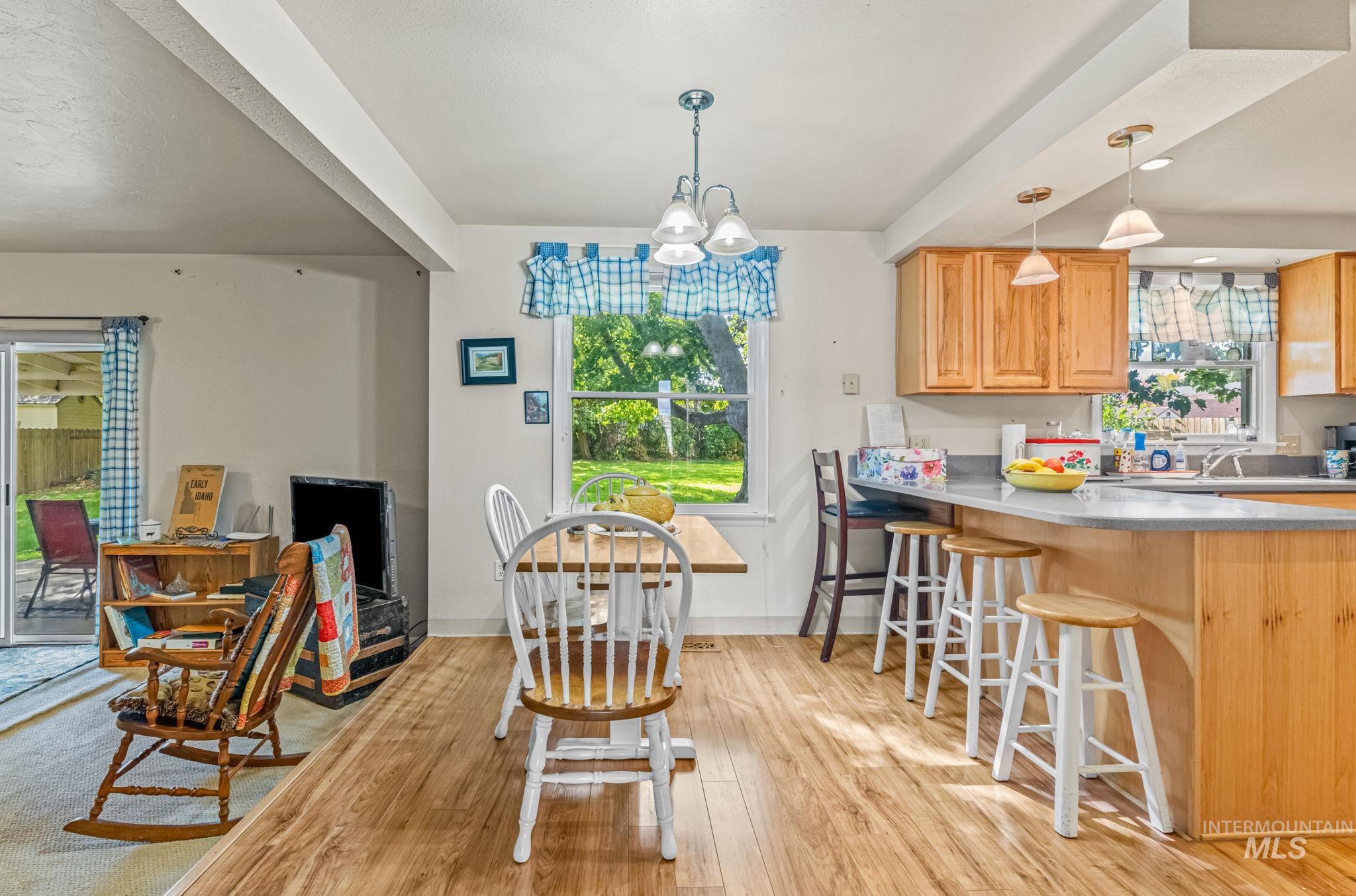 Dining area with healthy amount of natural light, beamed ceiling, a chandelier, and light wood-style floors