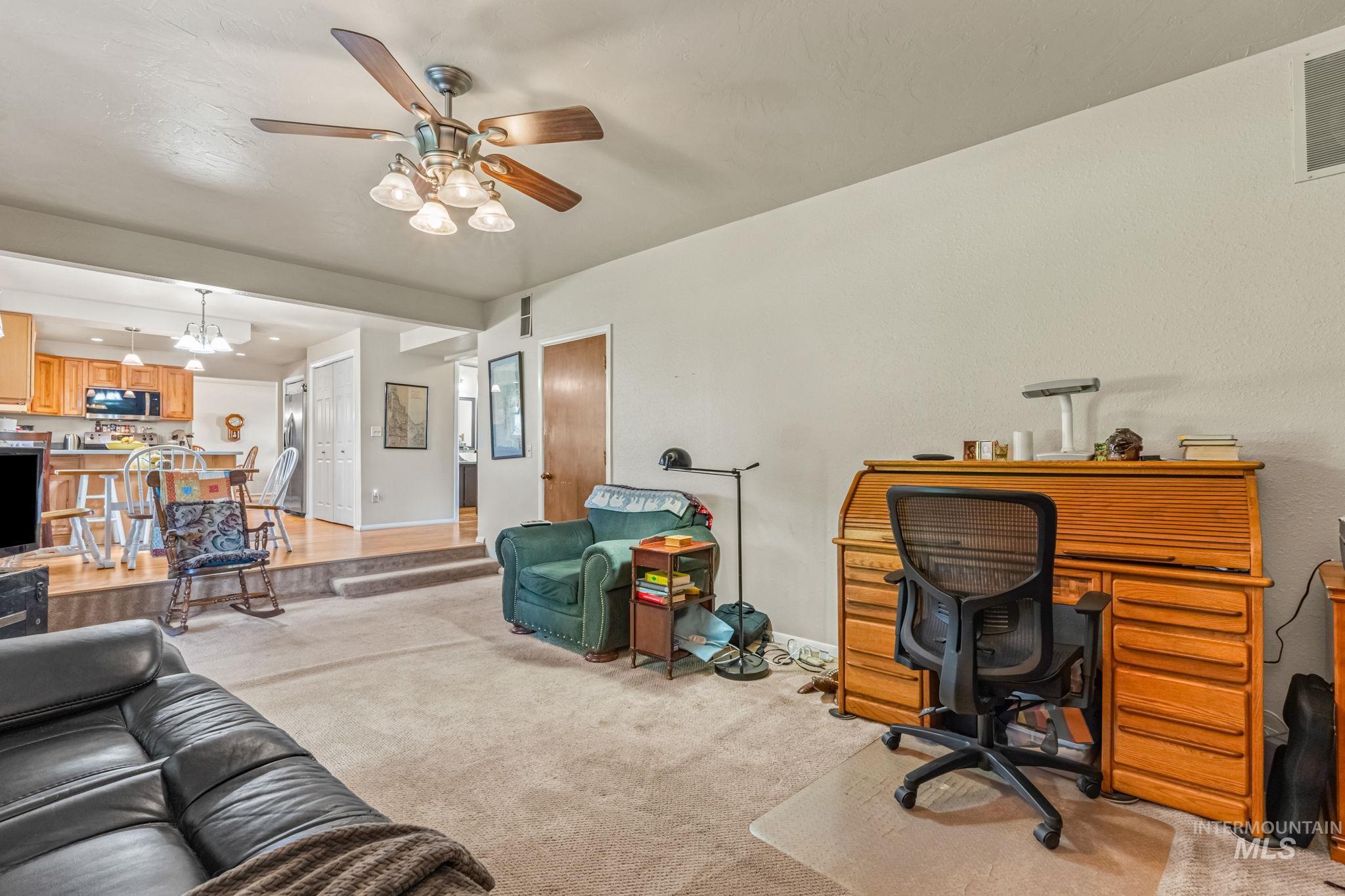 Office space with light colored carpet, ceiling fan, and a chandelier
