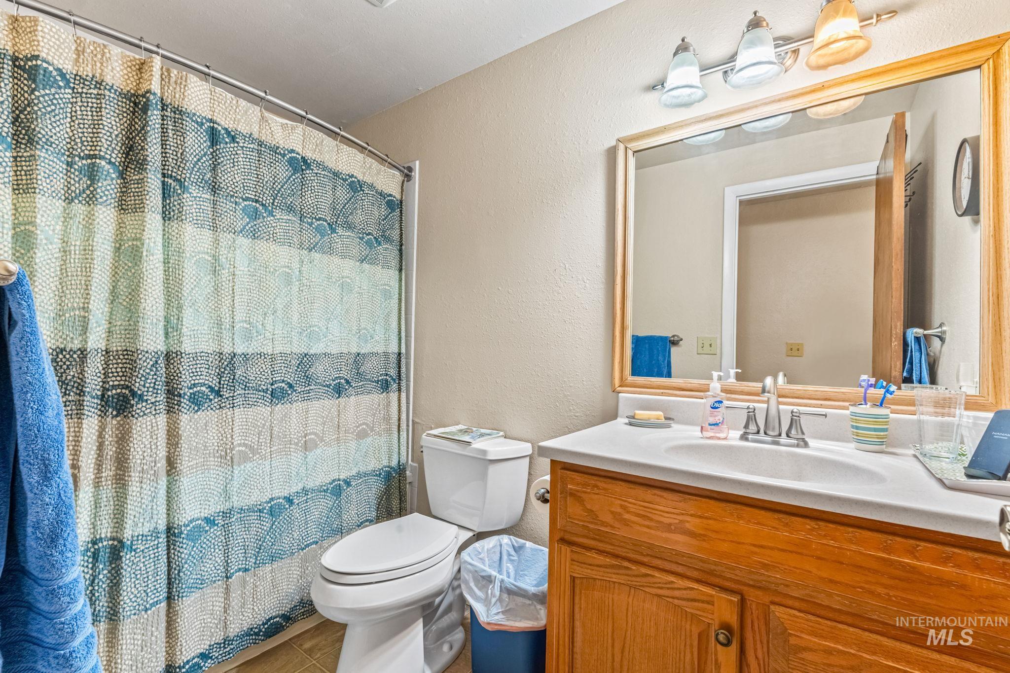 Full bathroom with a textured wall, vanity, and a shower with curtain