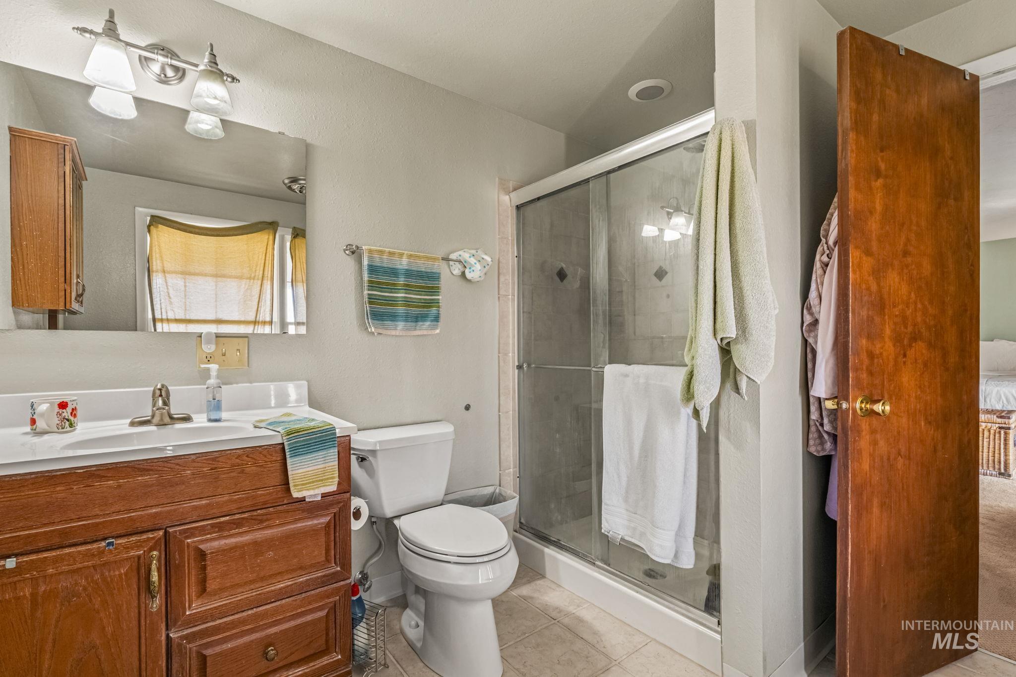 Full bathroom with vanity, light tile patterned flooring, and a shower stall