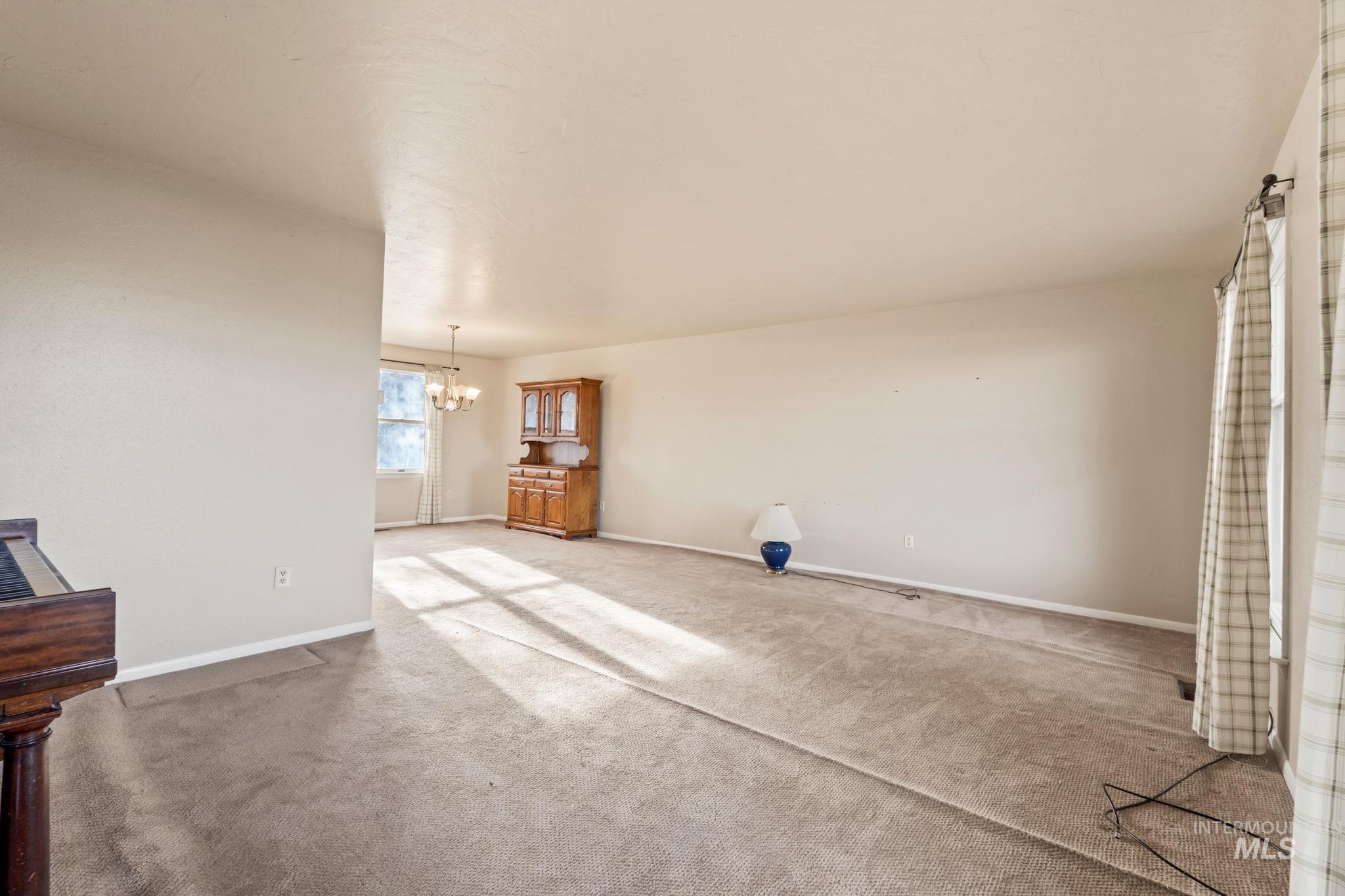Unfurnished living room with carpet floors and a chandelier