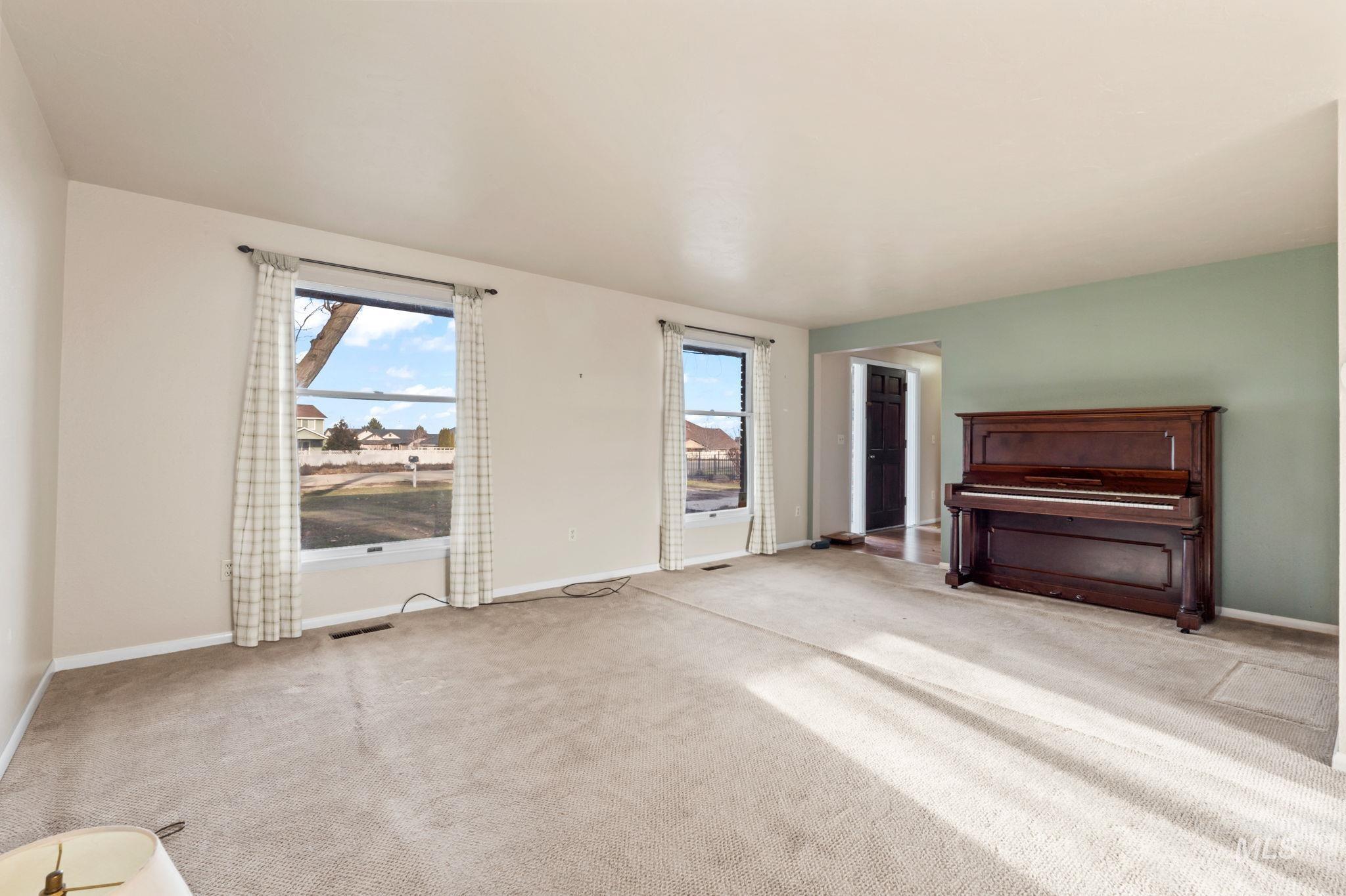 Unfurnished living room featuring light carpet and baseboards