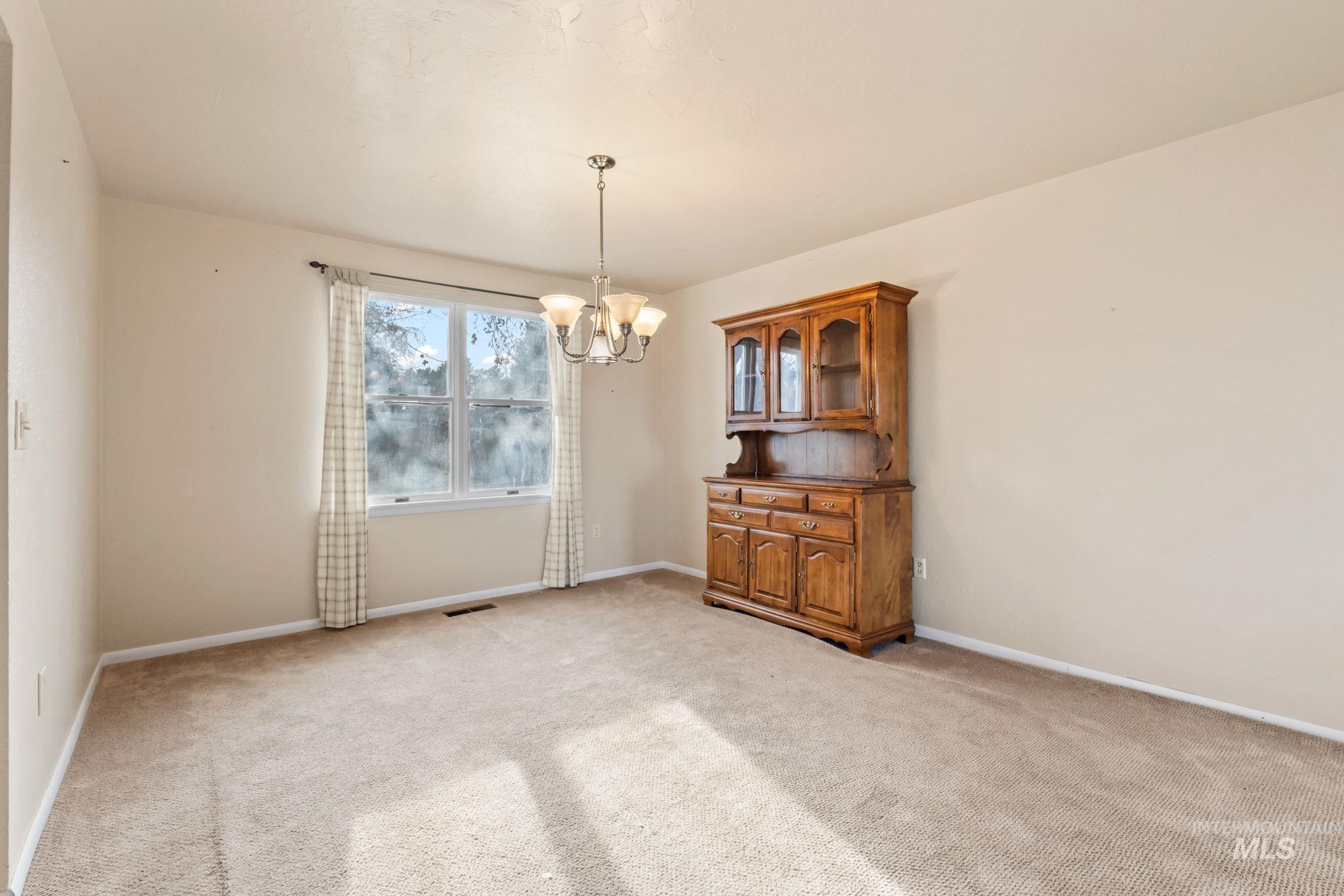 Unfurnished room with a chandelier and light carpet