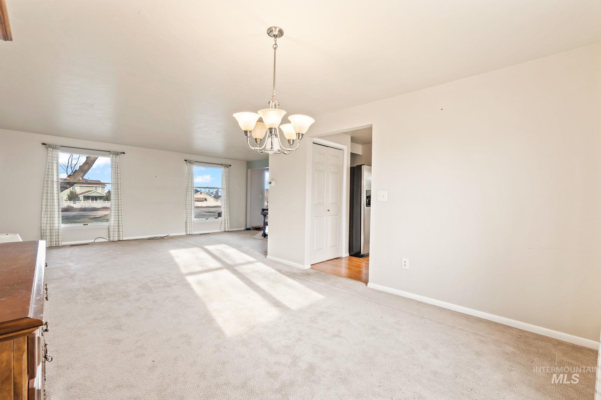 Unfurnished dining area with a chandelier and light colored carpet