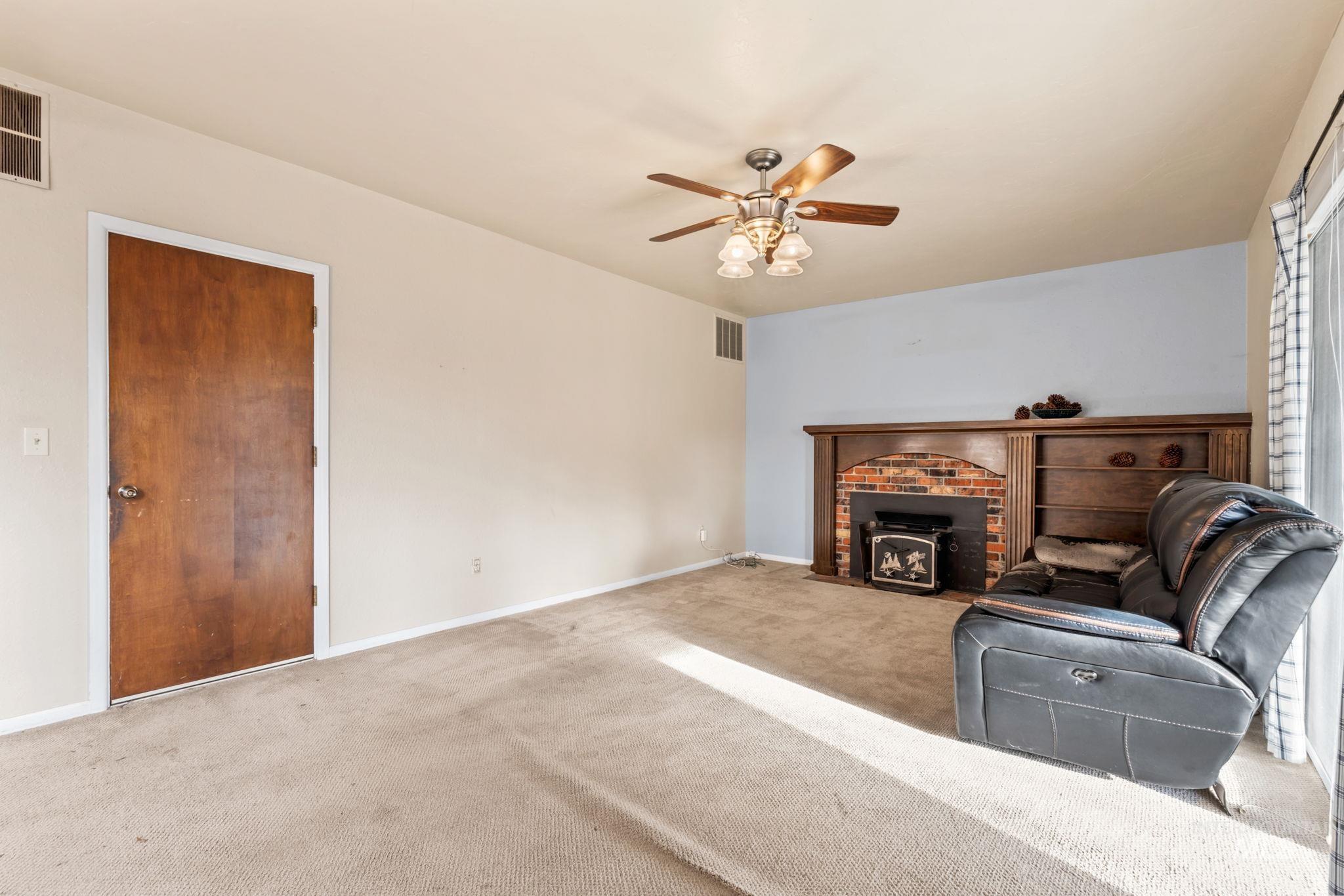 Carpeted living area with a wood stove and ceiling fan
