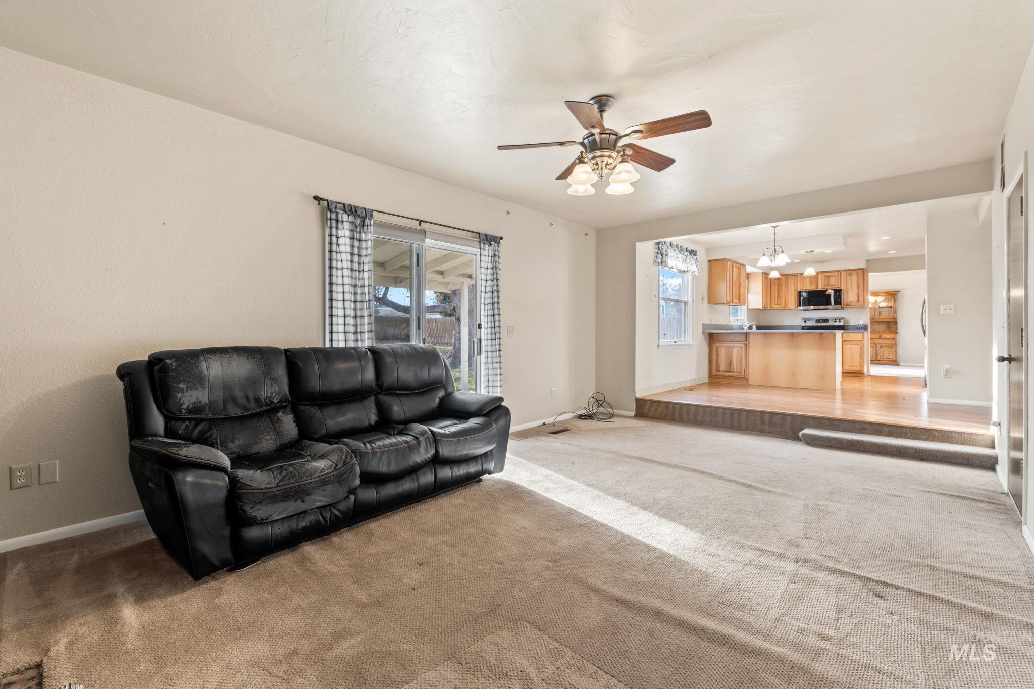 Living area with light carpet and a ceiling fan