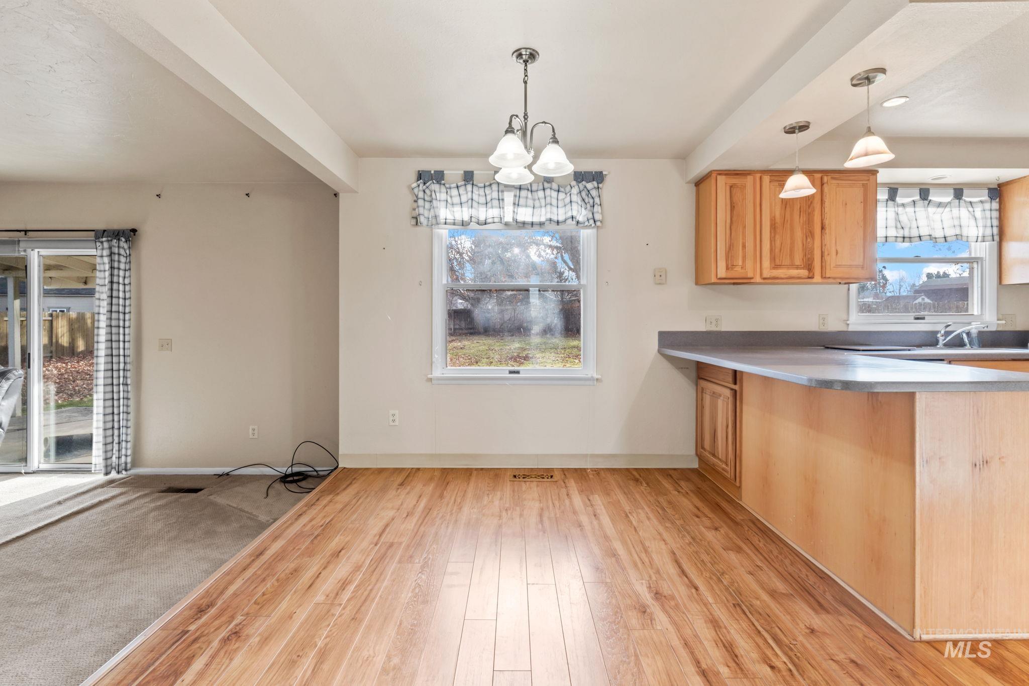 Kitchen with a chandelier, beam ceiling, light wood-style floors, a peninsula, and light countertops