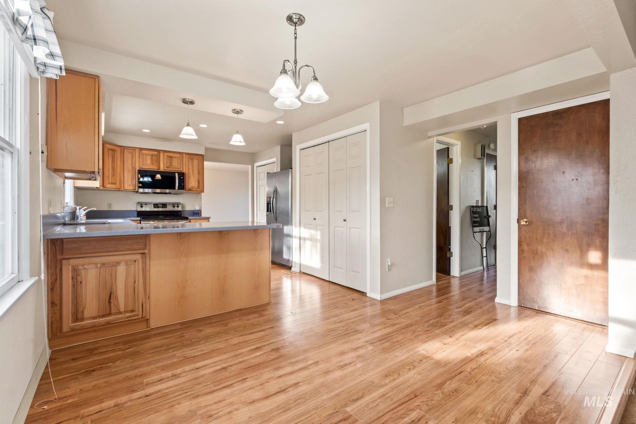 Kitchen featuring a peninsula, decorative light fixtures, stainless steel appliances, recessed lighting, and light wood-style floors