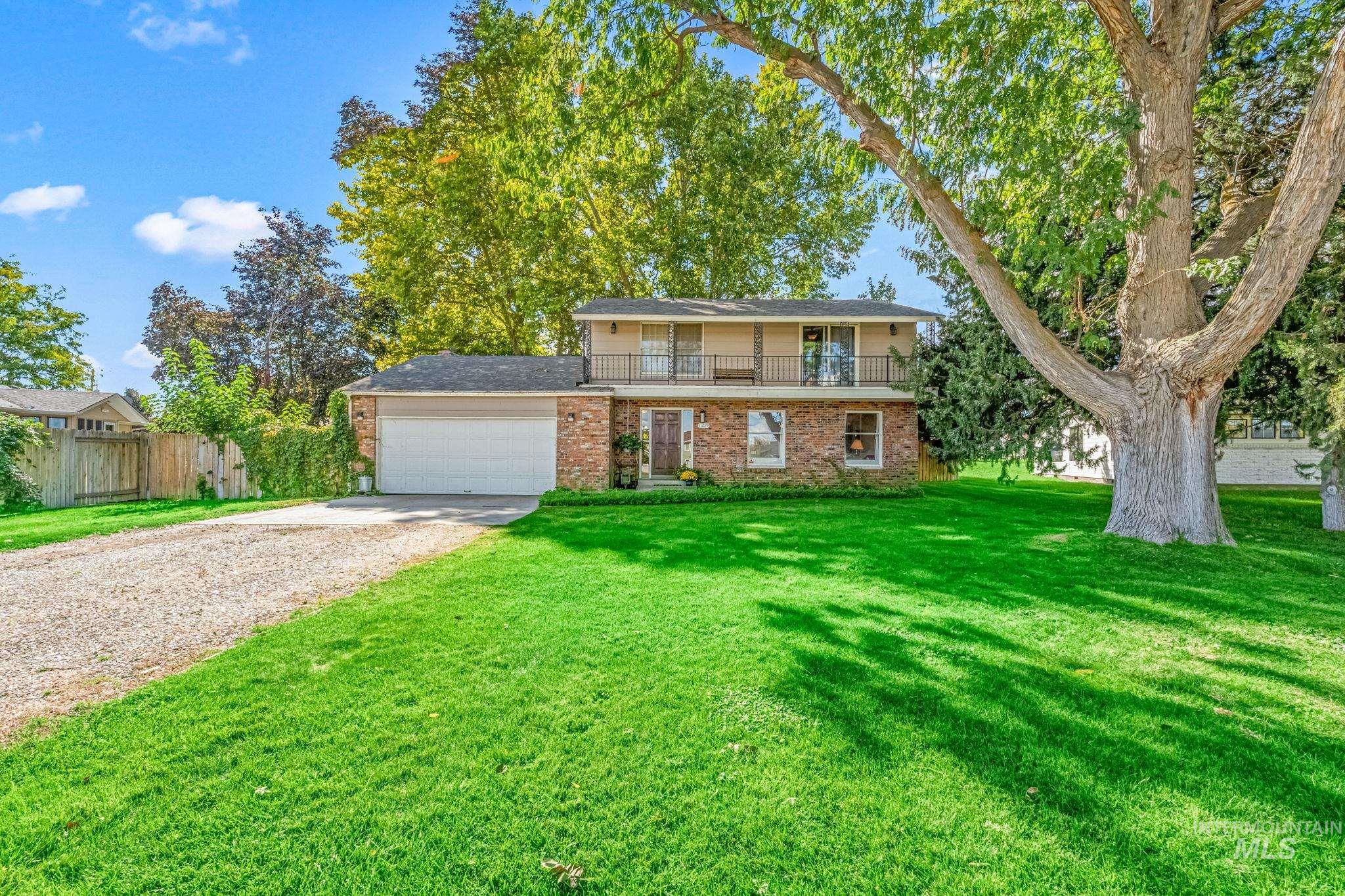 View of front of property with driveway, a balcony, brick siding, and a garage