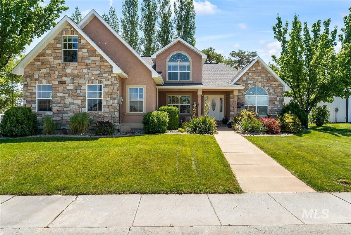 View of front of property featuring stone siding, a front lawn, and stucco siding