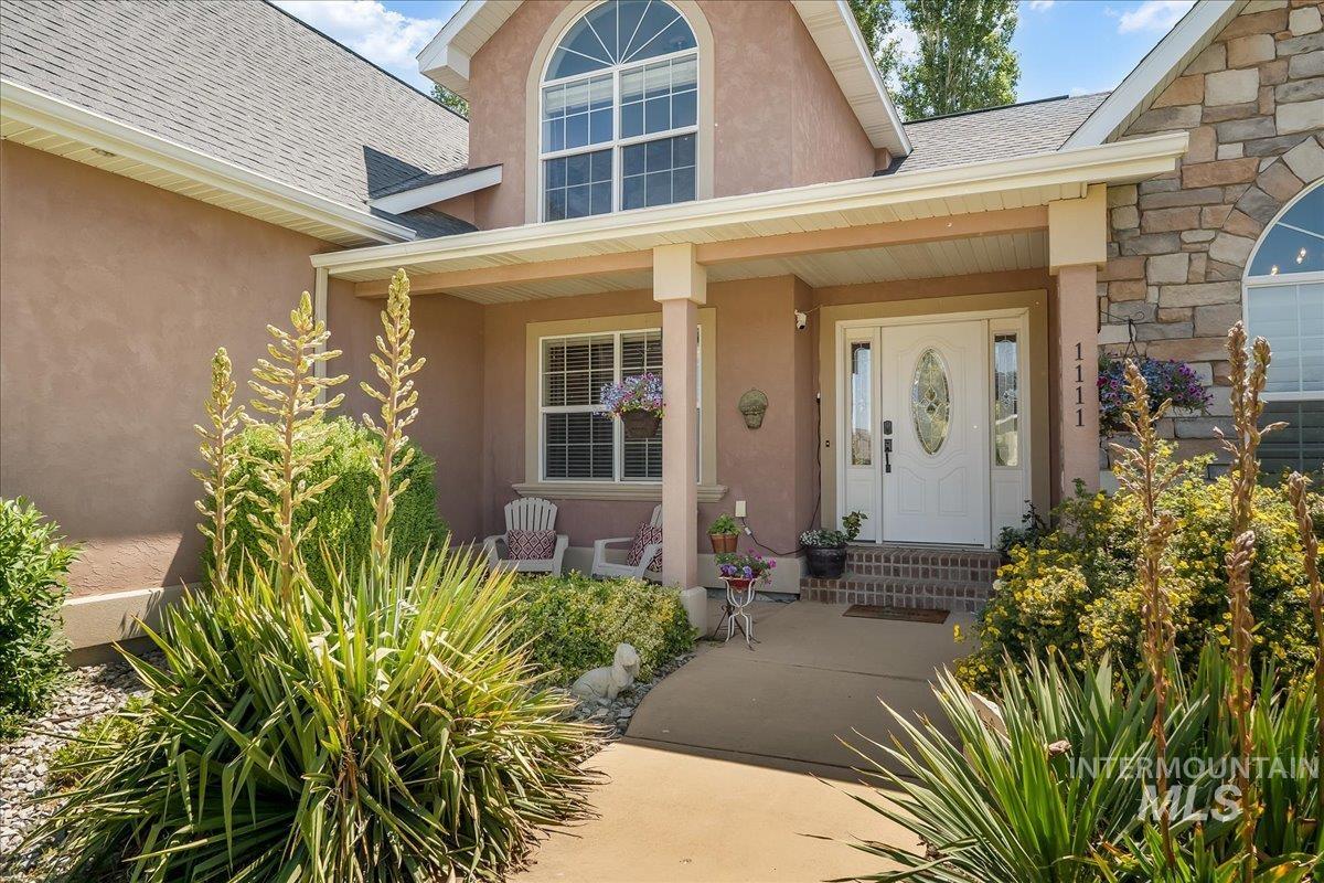 Entrance to property with roof with shingles, a porch, and stucco siding