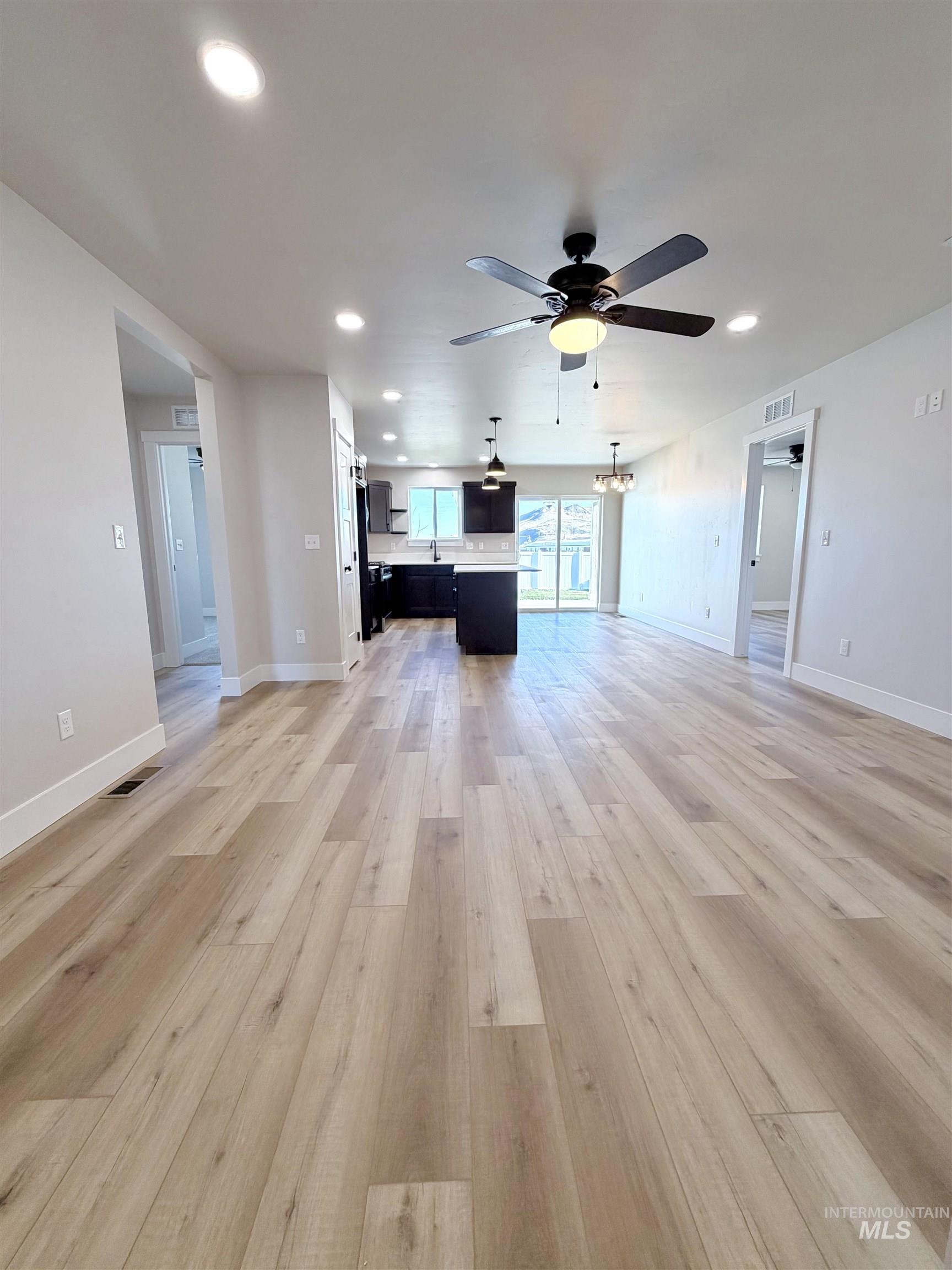 Unfurnished living room featuring recessed lighting, a chandelier, light wood-style floors, and ceiling fan