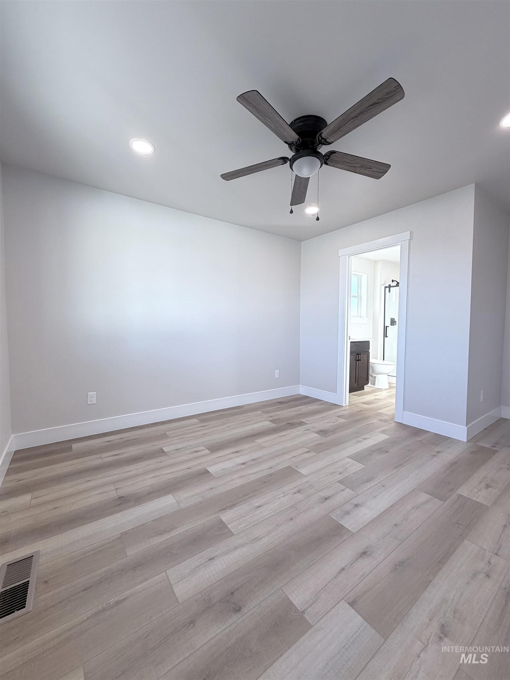 Unfurnished bedroom with recessed lighting, ceiling fan, light wood-type flooring, and ensuite bath