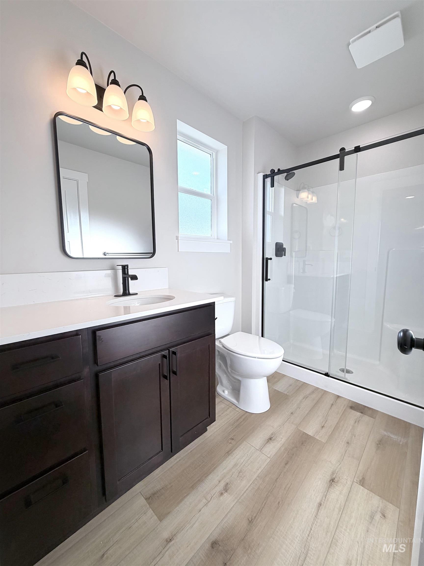 Full bath featuring vanity, a shower stall, and light wood-style floors
