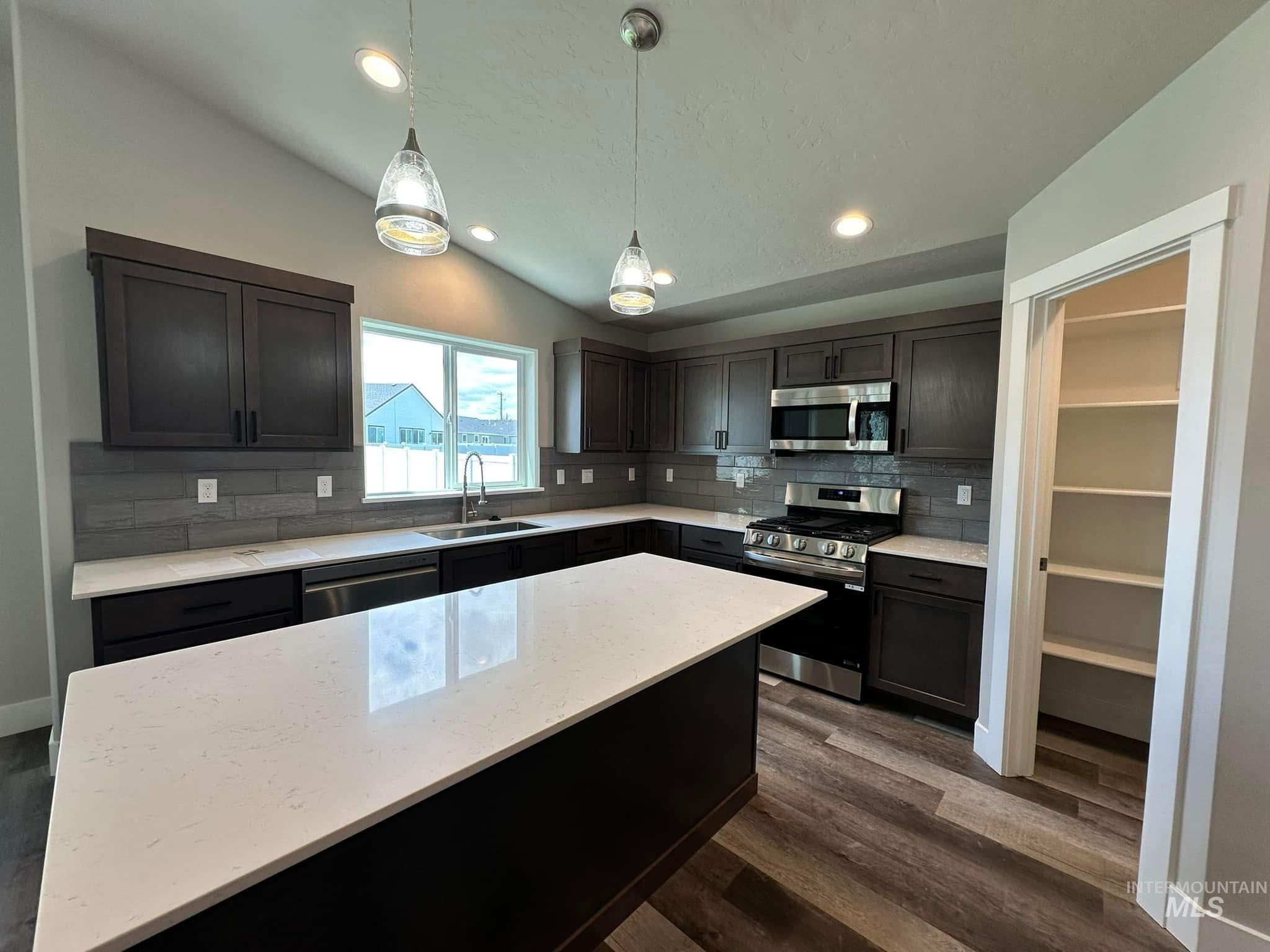 Kitchen featuring recessed lighting, stainless steel appliances, lofted ceiling, tasteful backsplash, and light stone counters