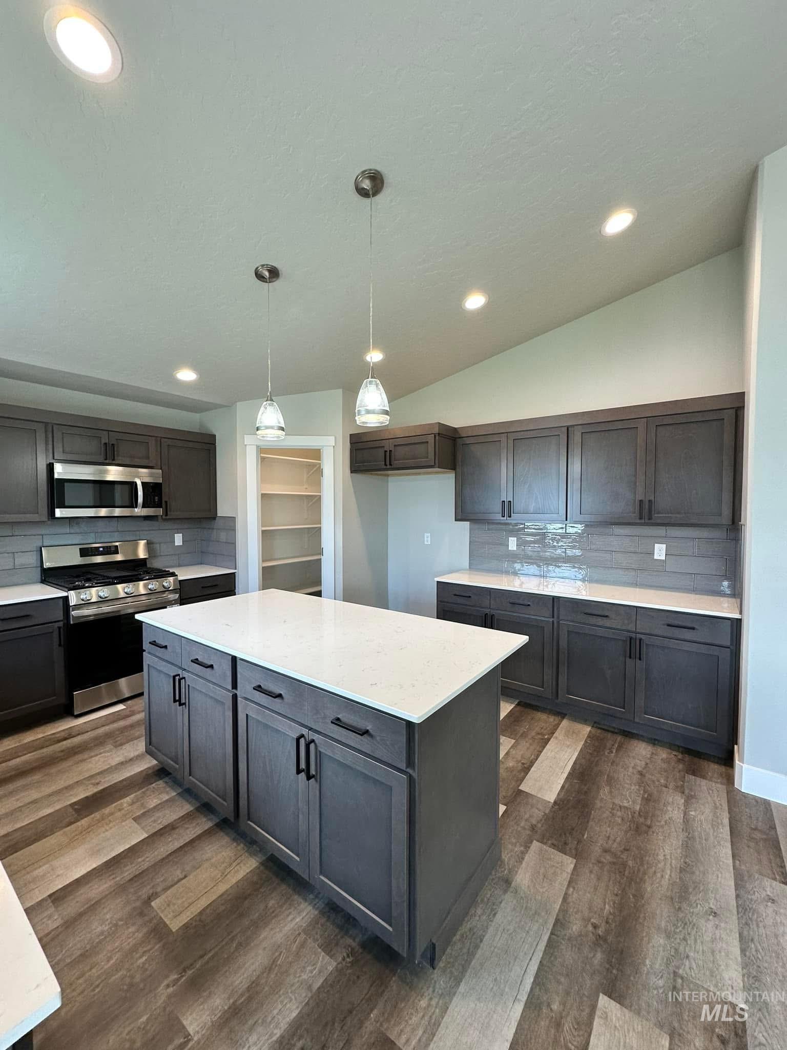 Kitchen featuring decorative backsplash, stainless steel appliances, pendant lighting, light stone counters, and recessed lighting