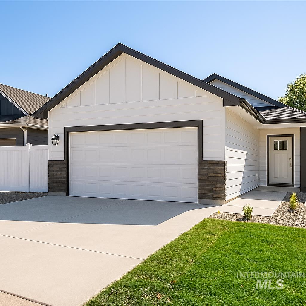 Ranch-style home featuring board and batten siding, concrete driveway, an attached garage, stone siding, and a front yard