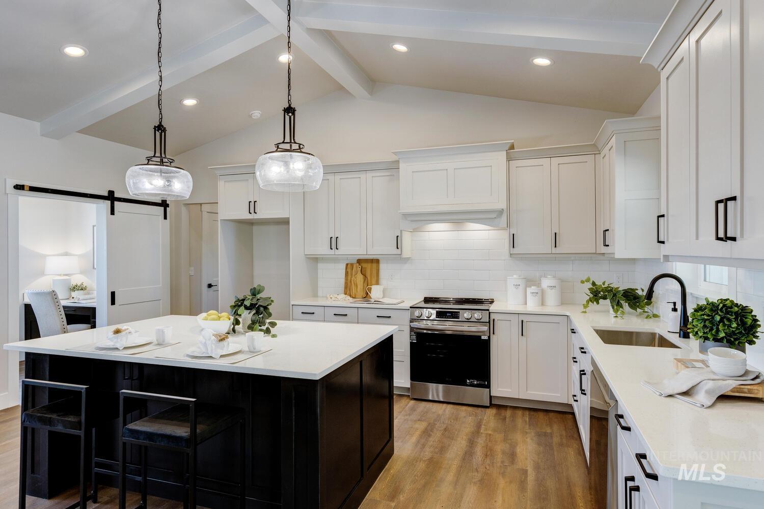 Kitchen with a barn door, stainless steel appliances, light countertops, light wood-type flooring, and white cabinetry