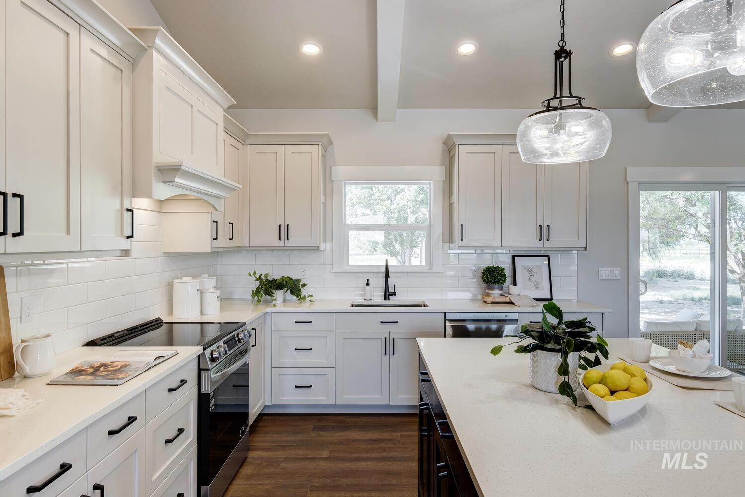 Kitchen with appliances with stainless steel finishes, light countertops, dark wood-type flooring, beam ceiling, and hanging light fixtures