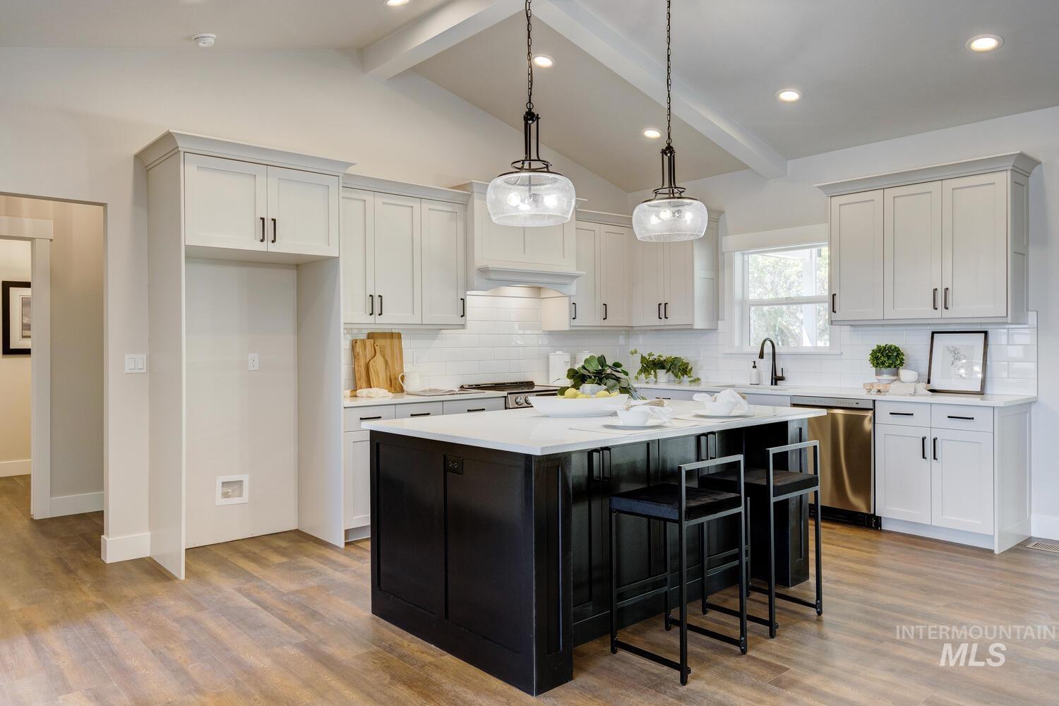 Kitchen with wood finished floors, light countertops, dishwasher, a kitchen island, and hanging light fixtures